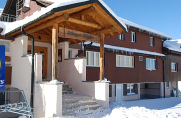 Berghaus in verschneiter Landschaft mit Holzarchitektur und Eingangsbereich.