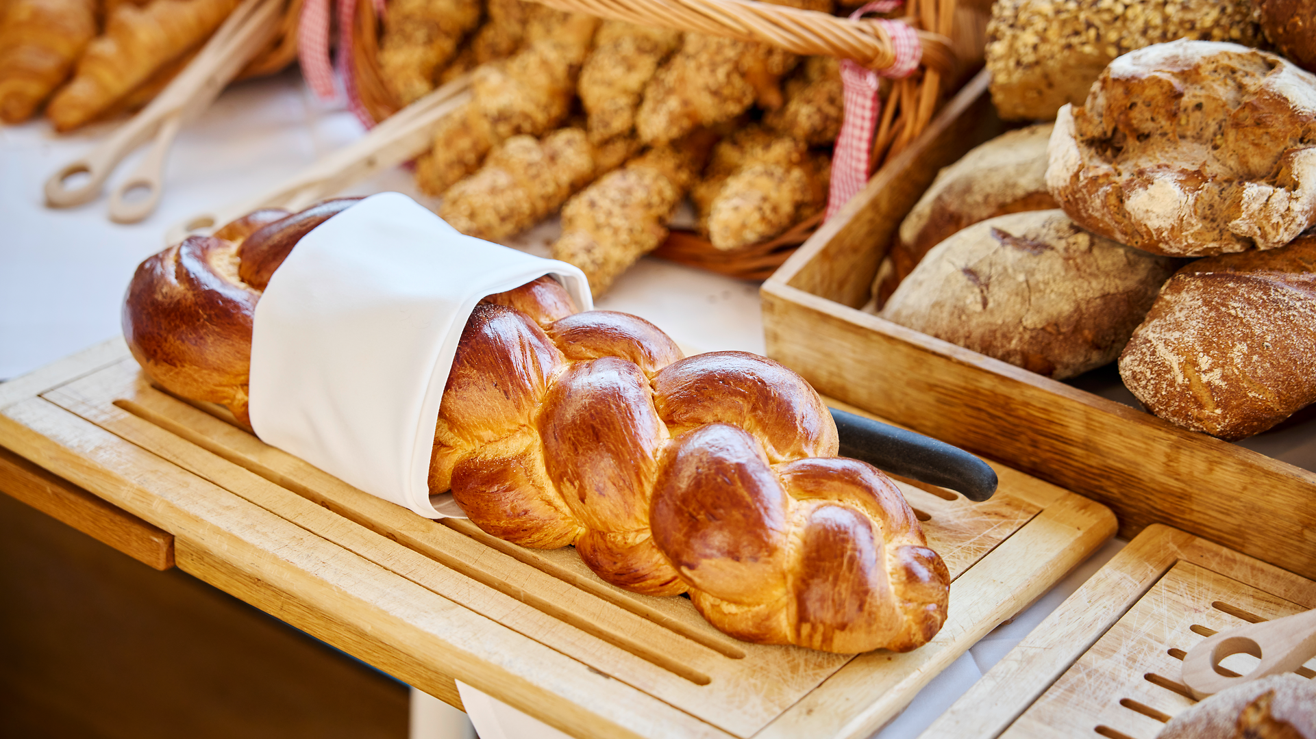Frisch gebackener Zopf und verschiedene Brotsorten auf einem Frühstücksbuffet an Bord eines Schiffes.