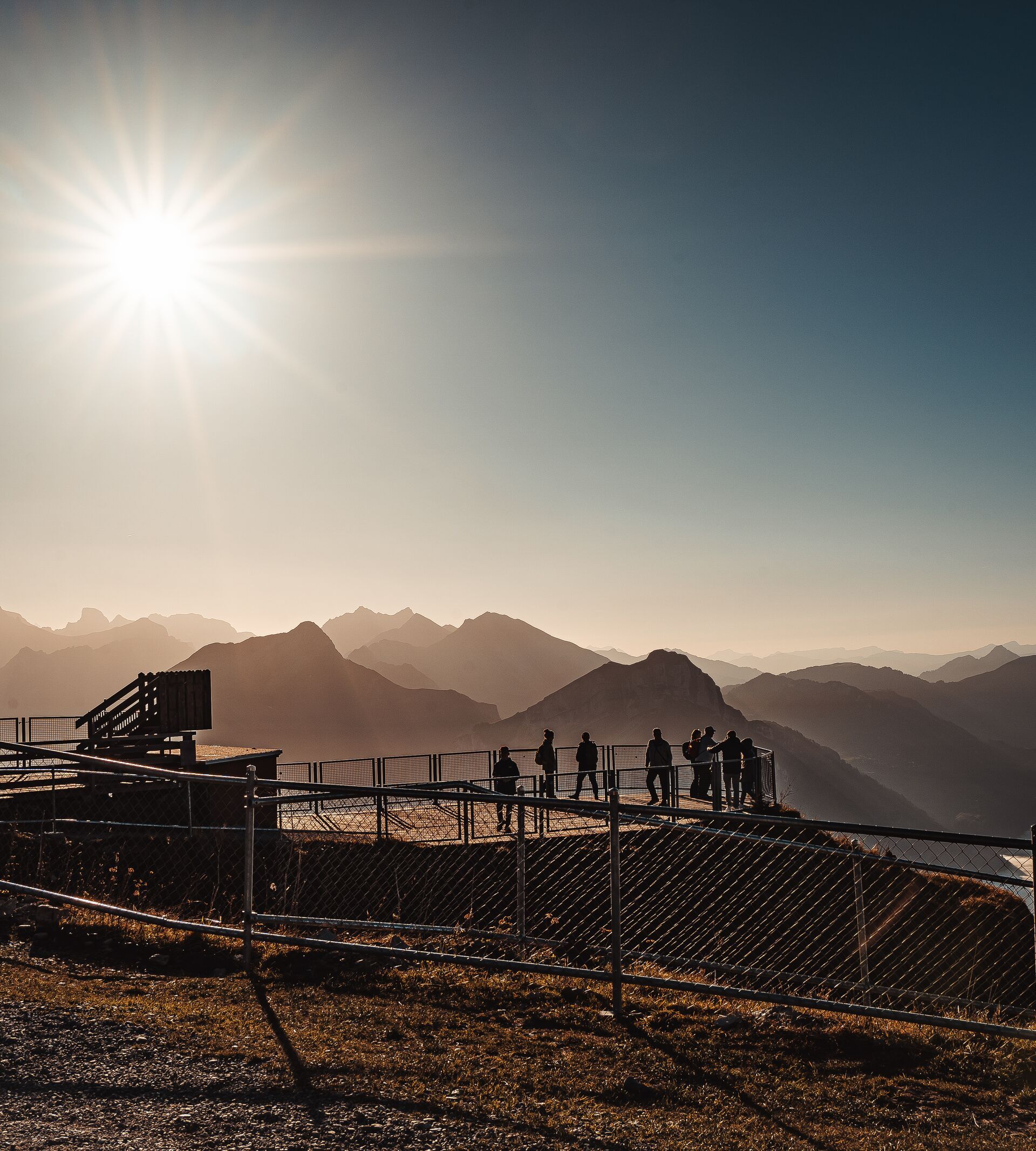 Aussichtsplattform am Fronalpstock mit Besuchern und Blick auf den Vierwaldstättersee und die umliegenden Berge im Gegenlicht.