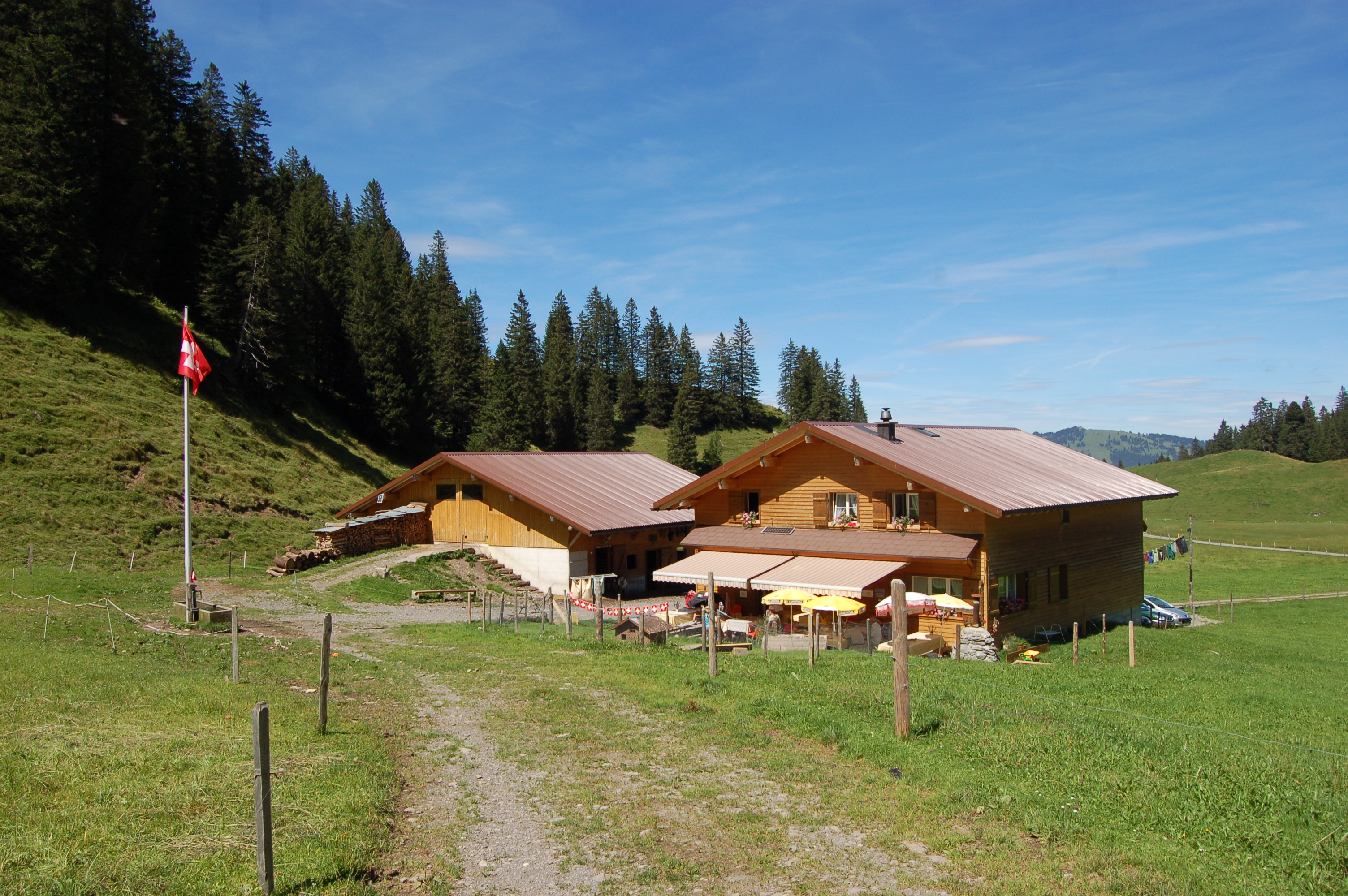 Alpgebäude auf einer Bergwiese mit Blick auf die umliegende alpine Landschaft.