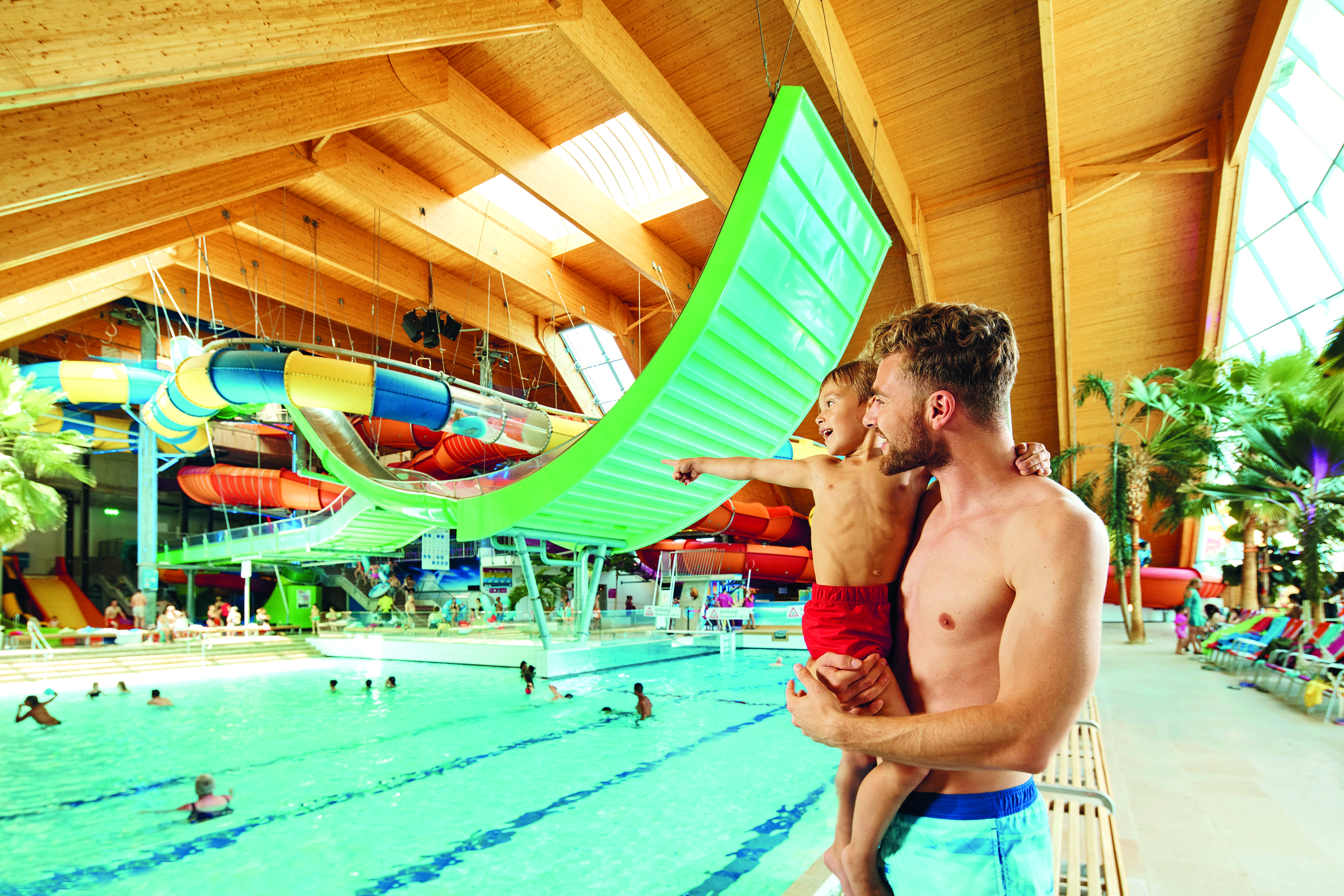 Vater hält seinen Sohn im Arm und blick auf das Schwimmbecken.