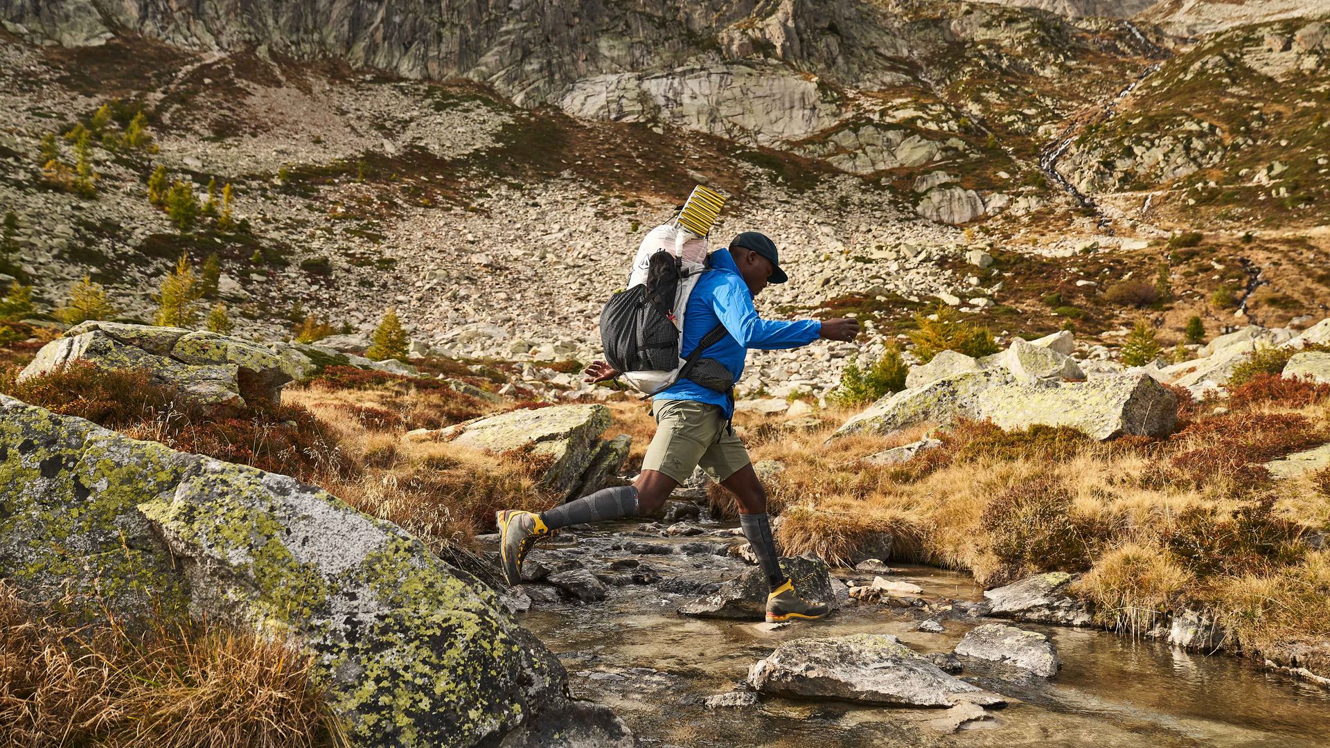 Un uomo con uno zaino sta sprintando su un torrente, mostrando agilità e determinazione in un ambiente naturale.