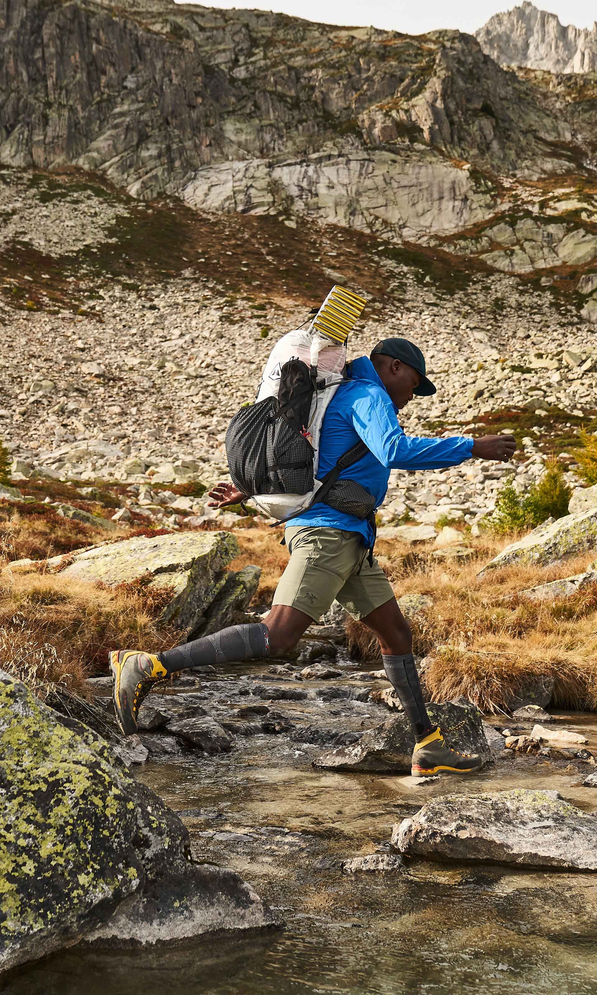 Un uomo con uno zaino sta sprintando su un torrente, mostrando agilità e determinazione in un ambiente naturale.