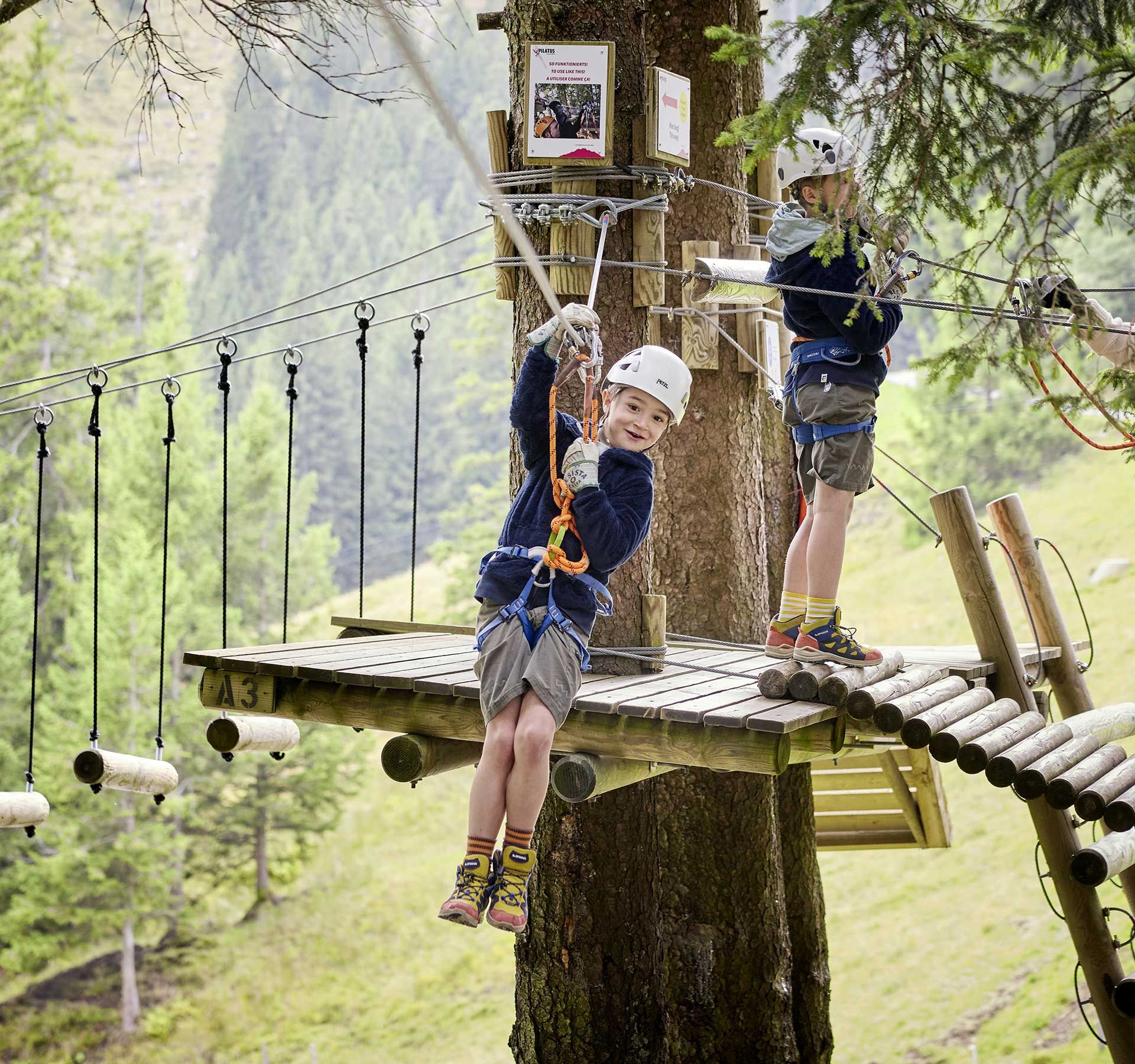 Un enfant sur une tyrolienne, entouré d'arbres dans la forêt. Une expérience passionnante en pleine nature.