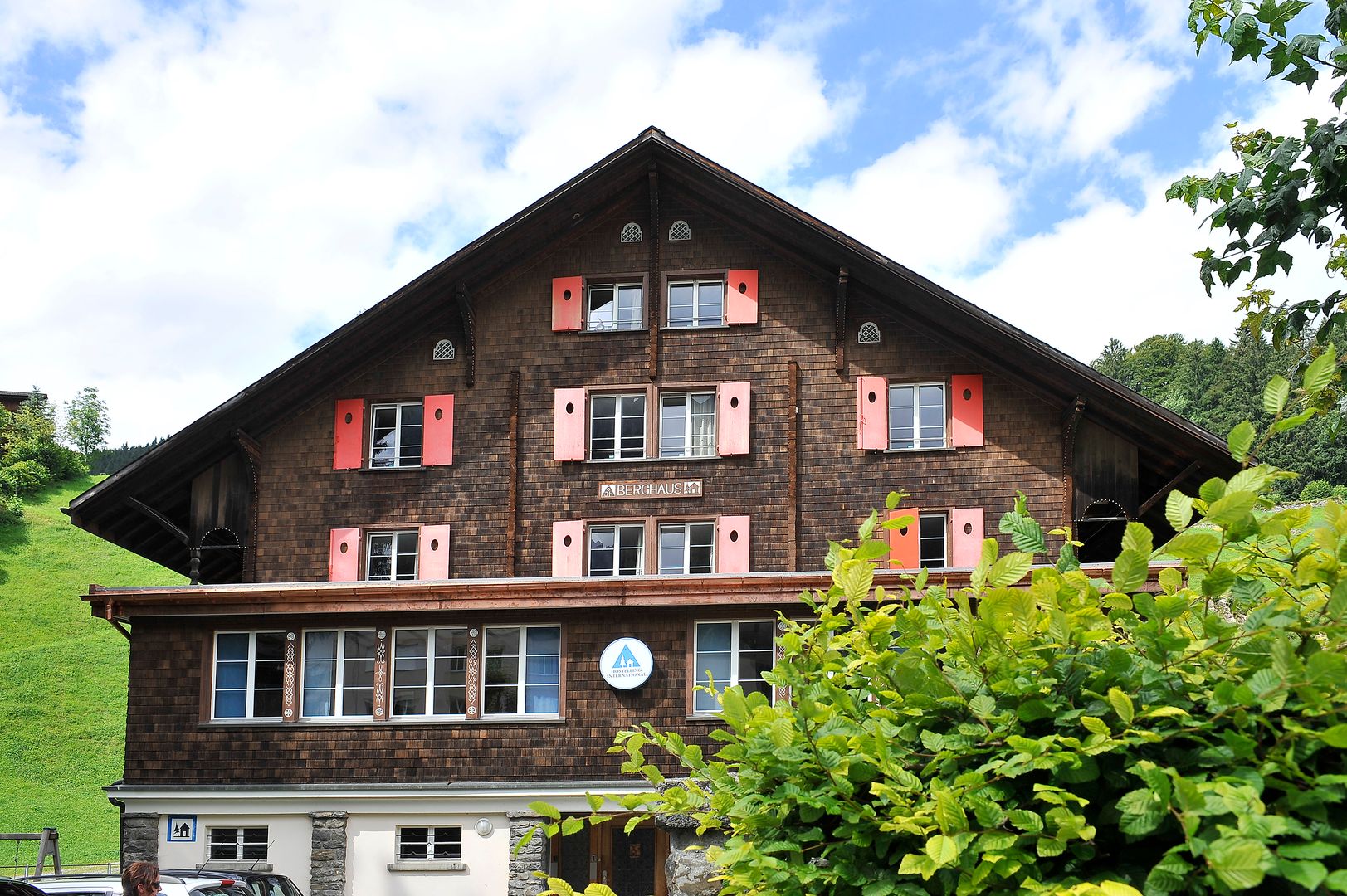 Die Vorderseite einer Ferienunterkunft an der das Schild Berghaus und das Logo der Schweizer Jugendherbergen zu sehen sind.