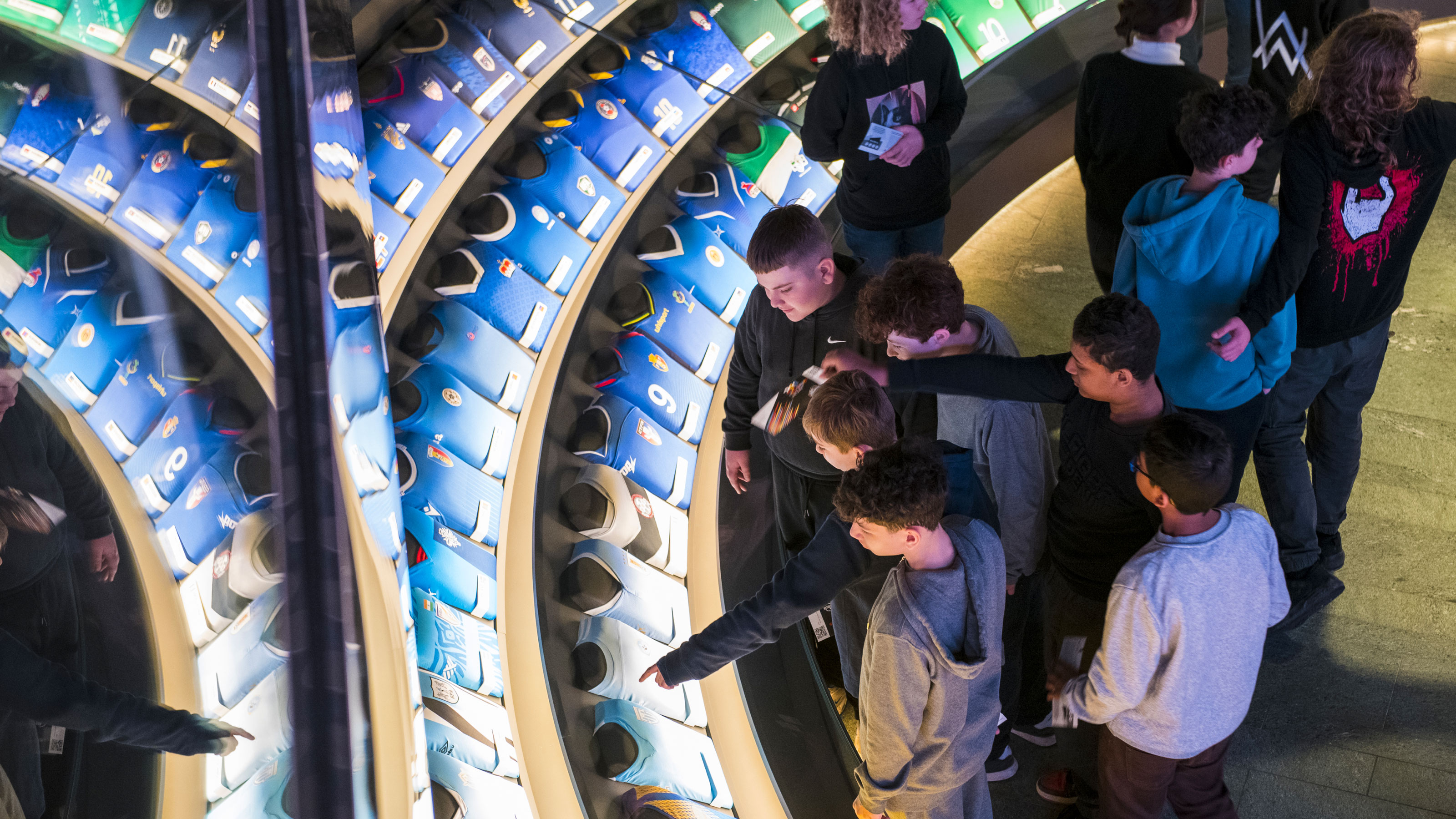 Vista interna del Museo della FIFA. Il gruppo di ragazzi guarda le diverse maglie.