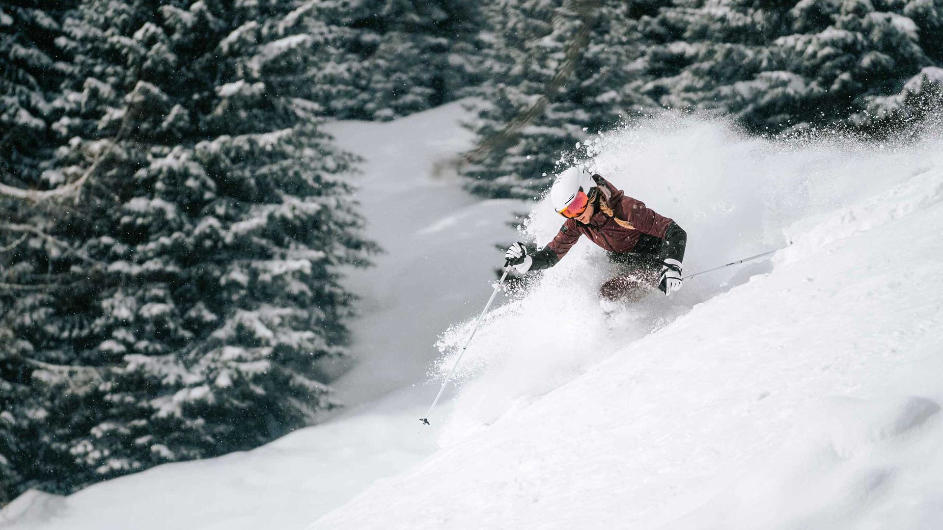 Una persona scia abilmente lungo un pendio innevato, mettendo in mostra la propria tecnica sullo sfondo di un paesaggio invernale.