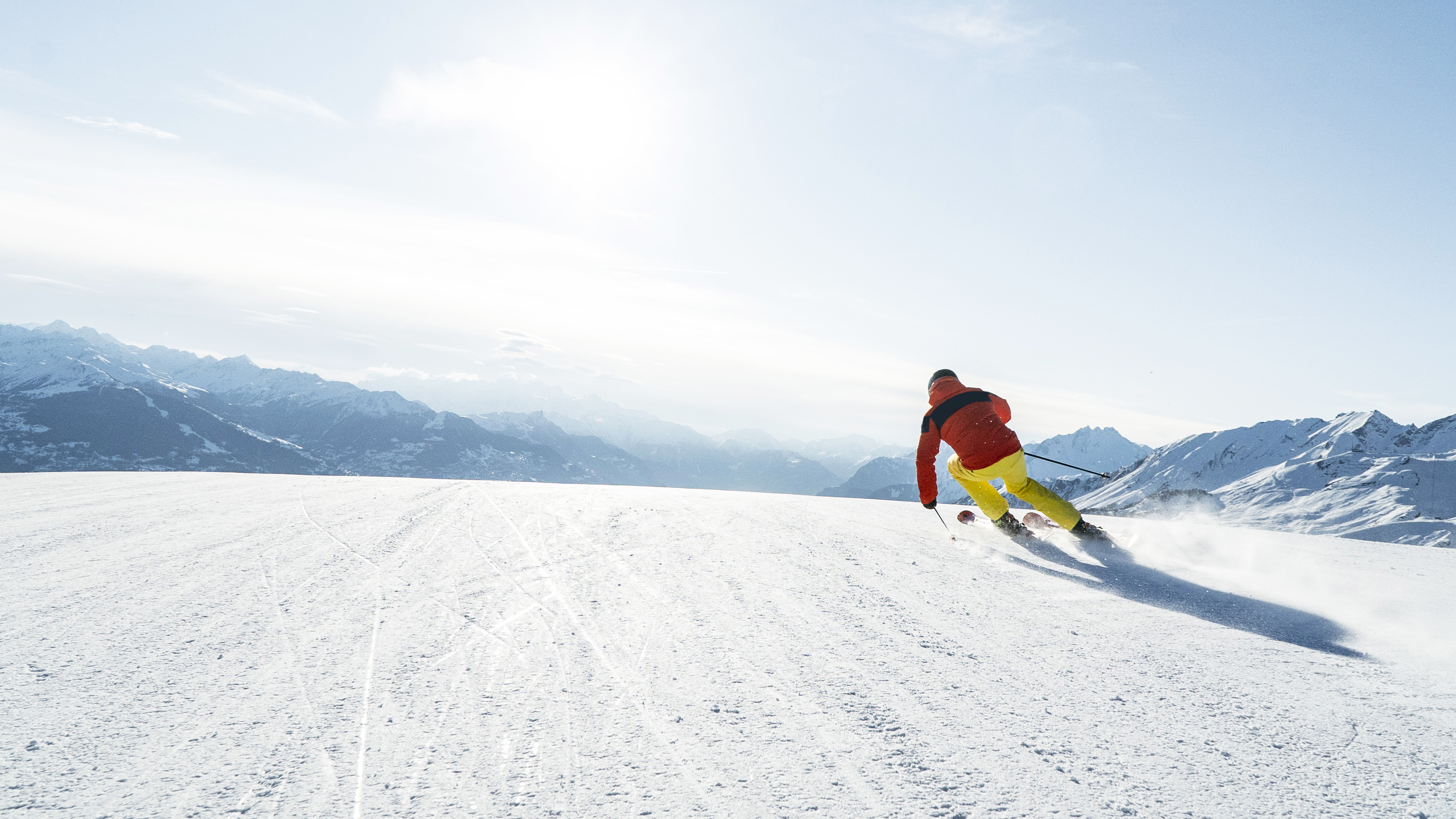 Uno sciatore scende lungo la pista davanti a un panorama montano mozzafiato.