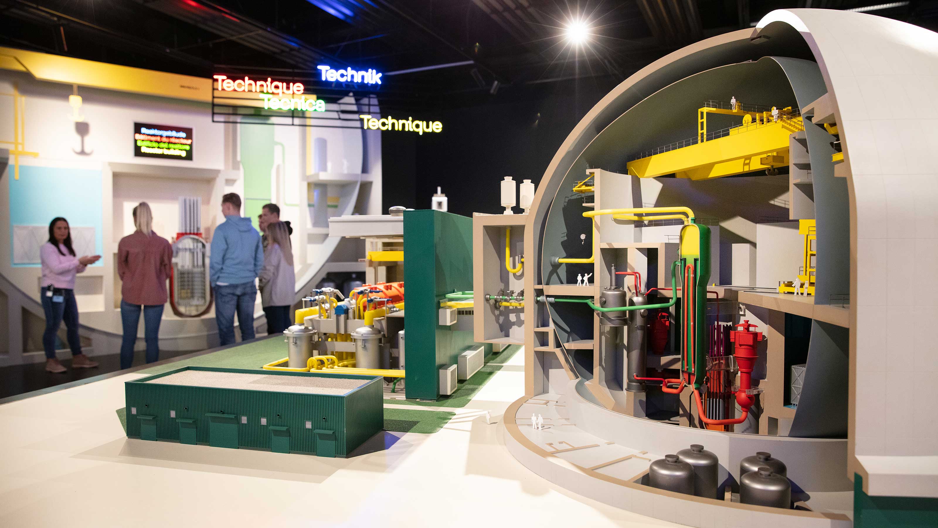 A model shows the interior of the nuclear power plant. In the background is a group of people who follow the guide attentively.