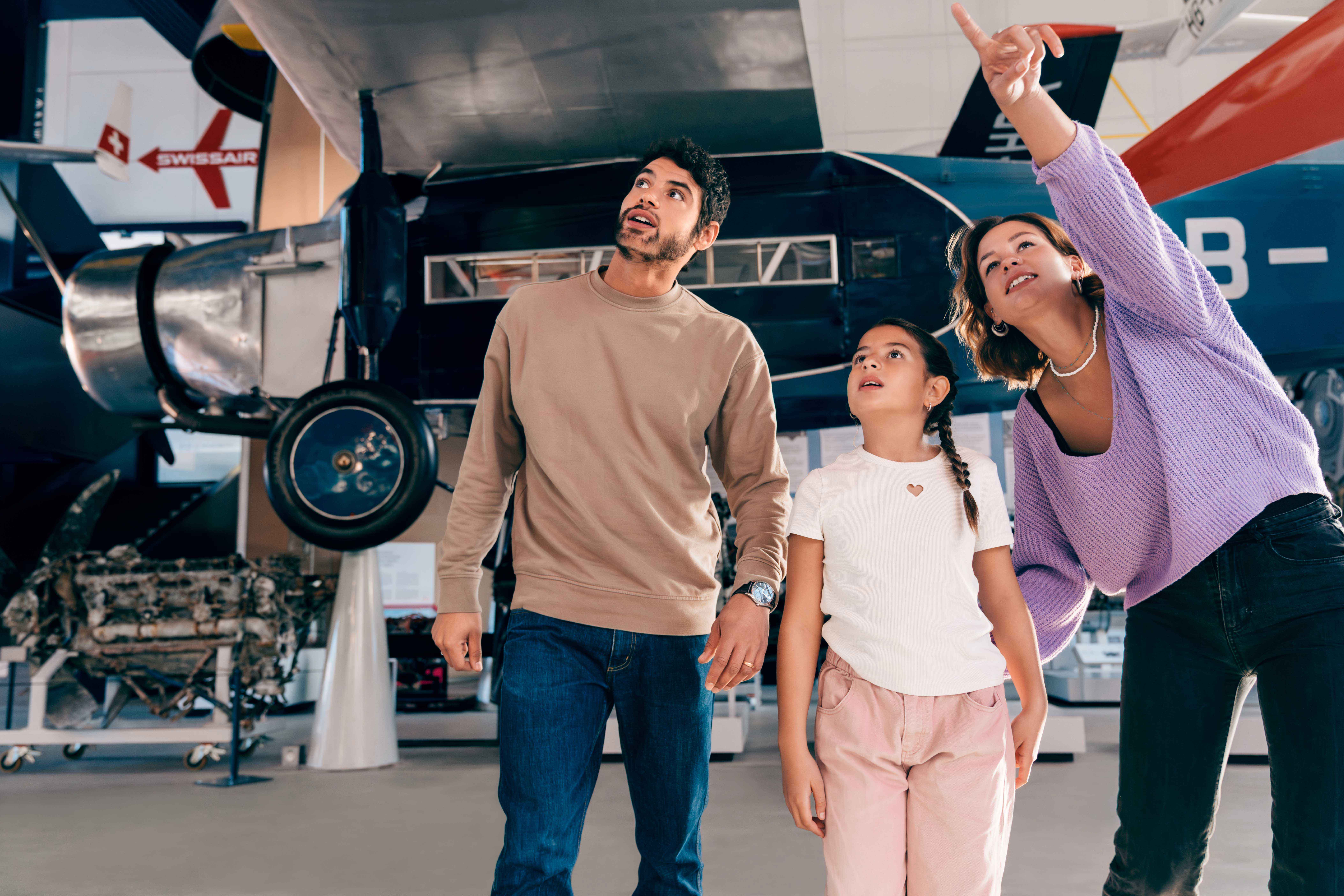 A family looks at an airplane in a museum.