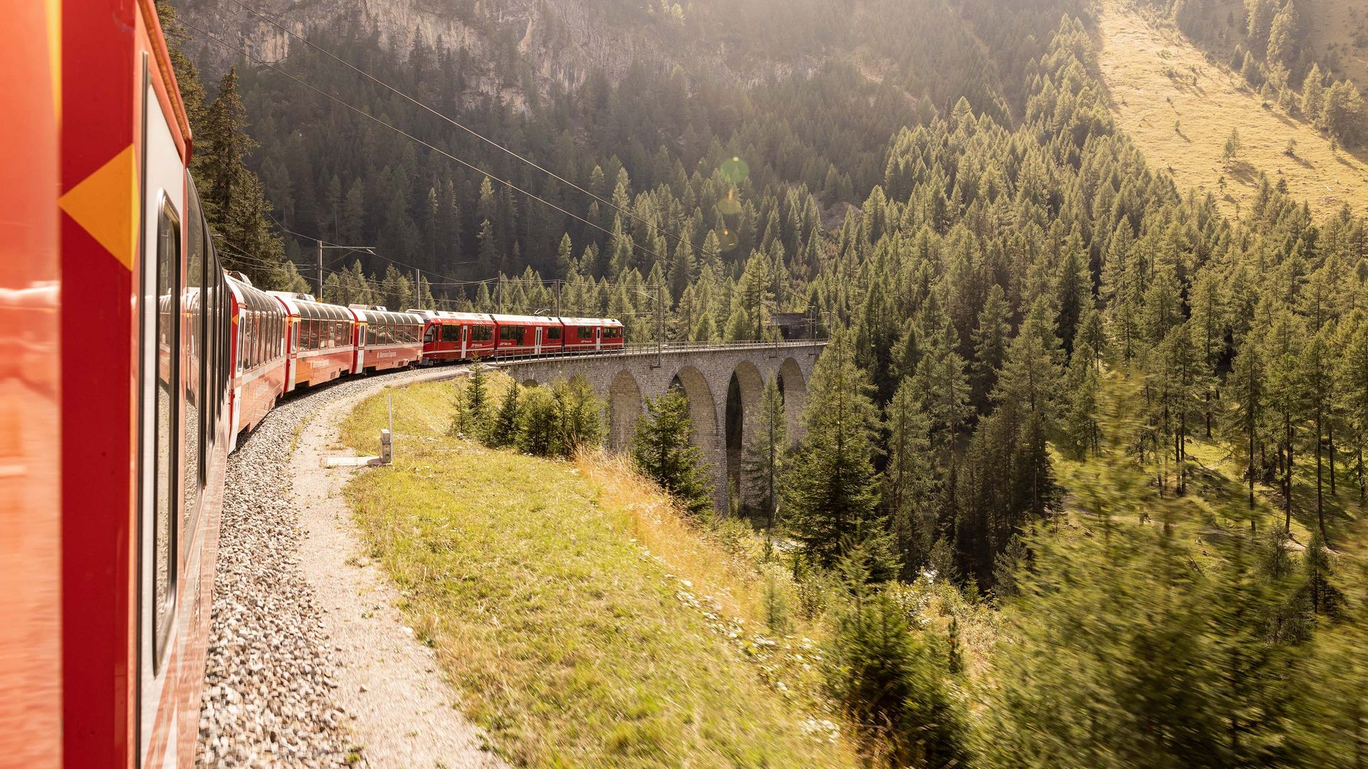 Il treno panoramico Bernina Express si snoda lungo la storica linea ferroviaria tra boschi e pareti rocciose.