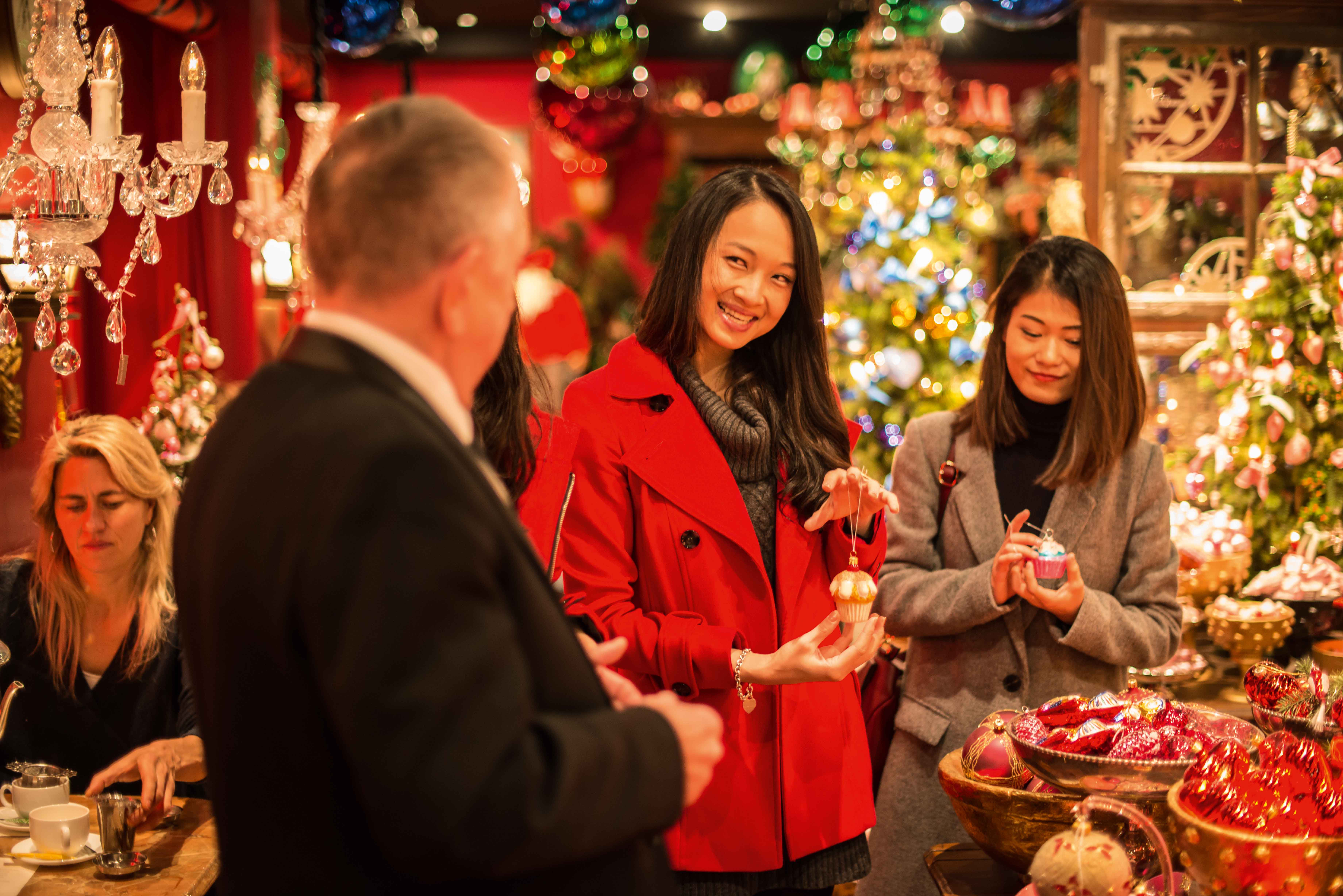 Two women stand together in front of a beautifully decorated Christmas tree, sharing a joyful moment during the holiday season.