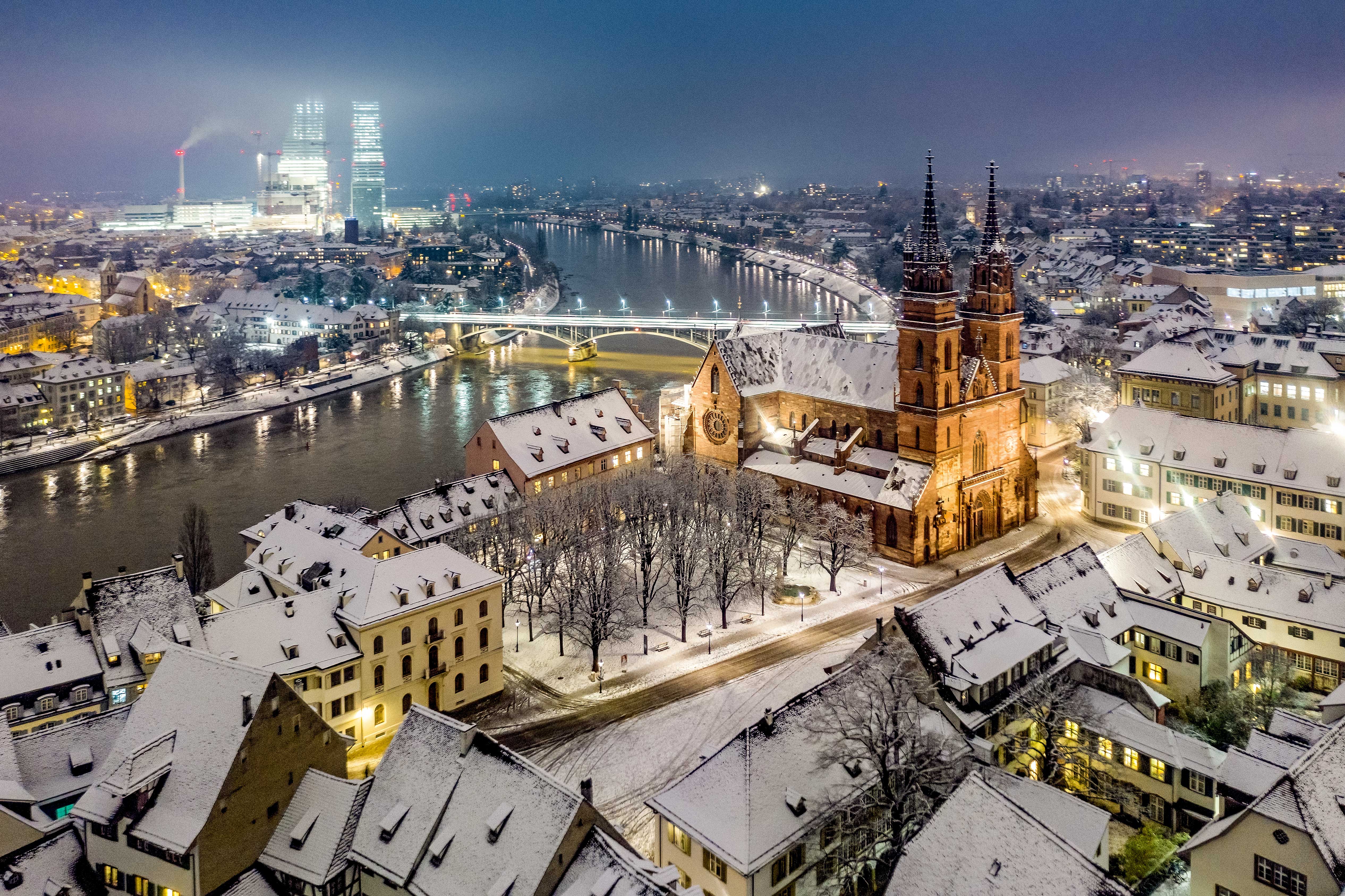 Un pittoresco paesaggio urbano con edifici innevati e un fiume che scorre sereno.