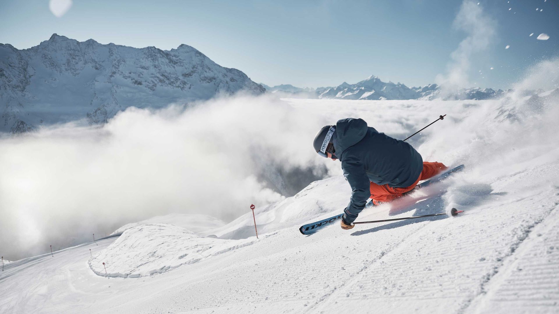 Ein Skifahrer fährt einen verschneiten Hang hinunter.