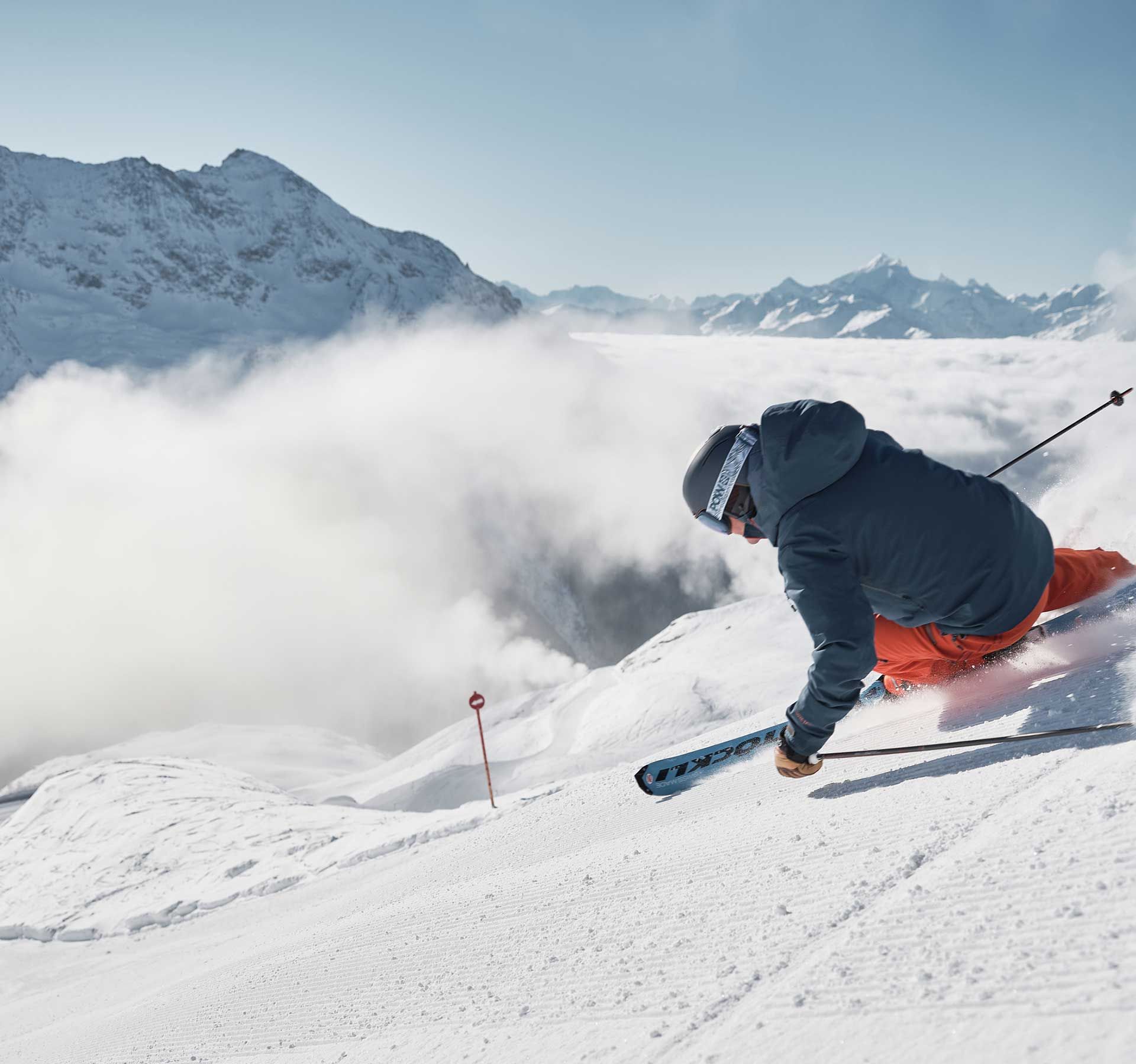 Ein Skifahrer fährt einen verschneiten Hang hinunter.