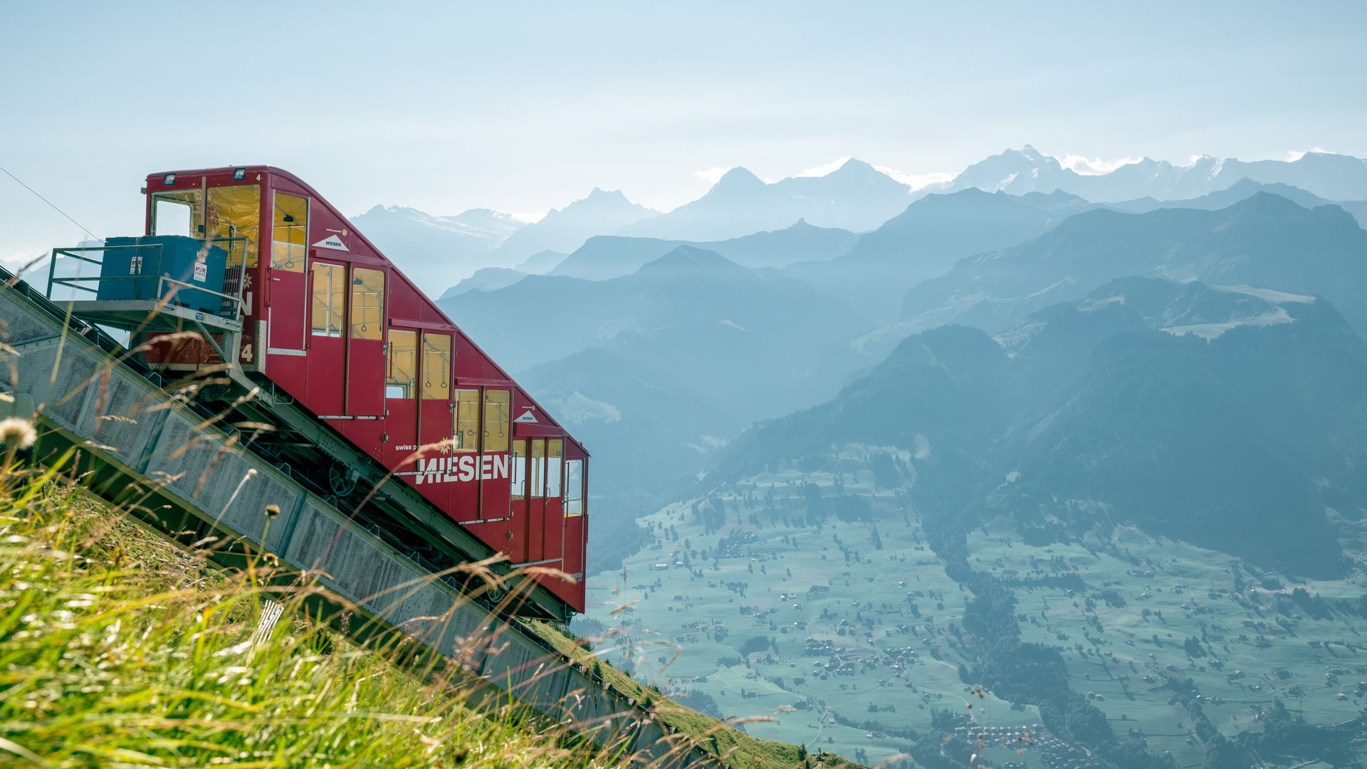 Die Standseilbahn fährt den steilen Niesen hinauf. Die Aussicht ist phänomenal und reicht bis weit an den Horizont. Zu sehen sind diverse Berggifpel.