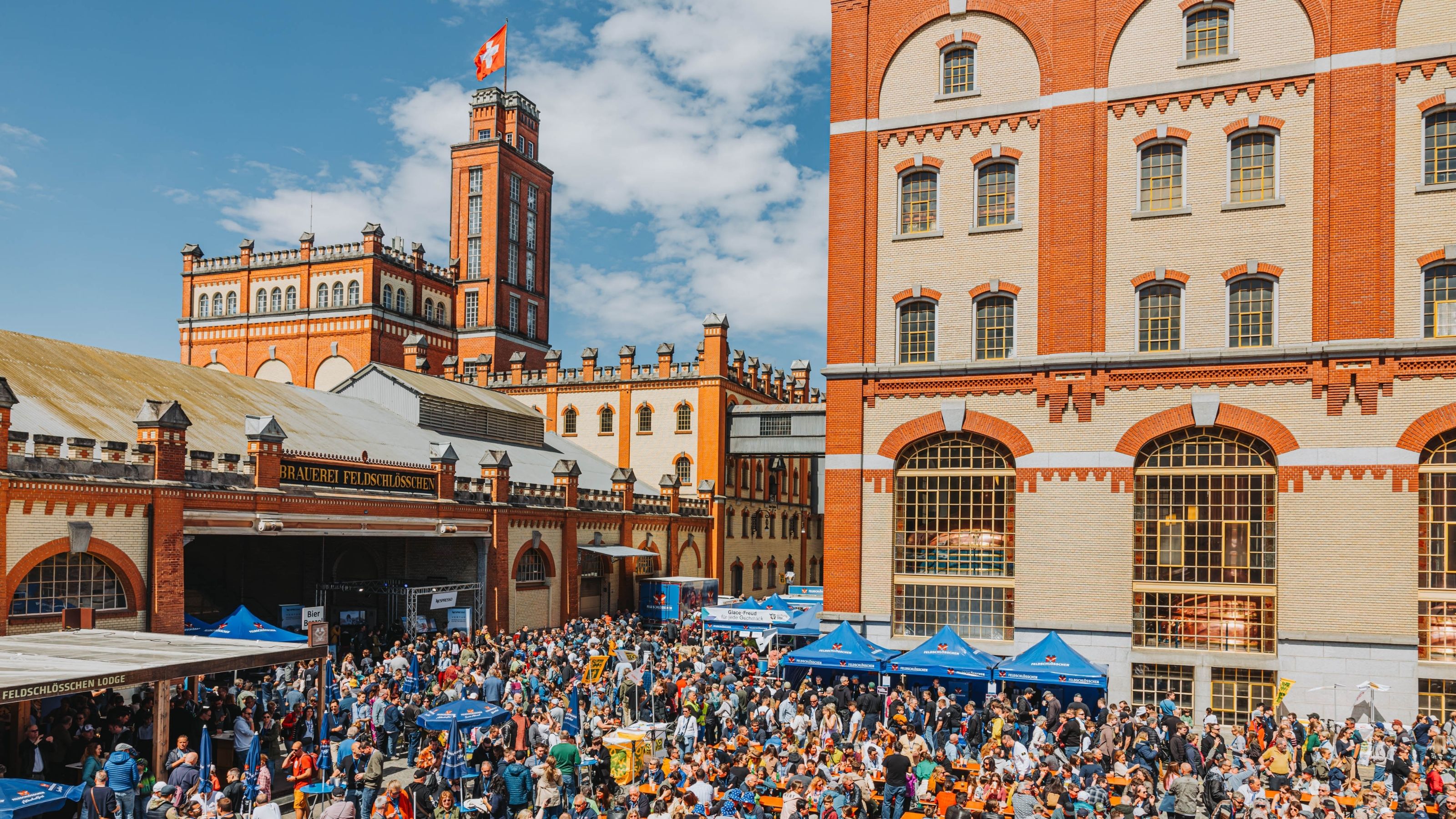 Des gens profitent du Feldschlösschen Brauereifest en plein air sous le soleil.