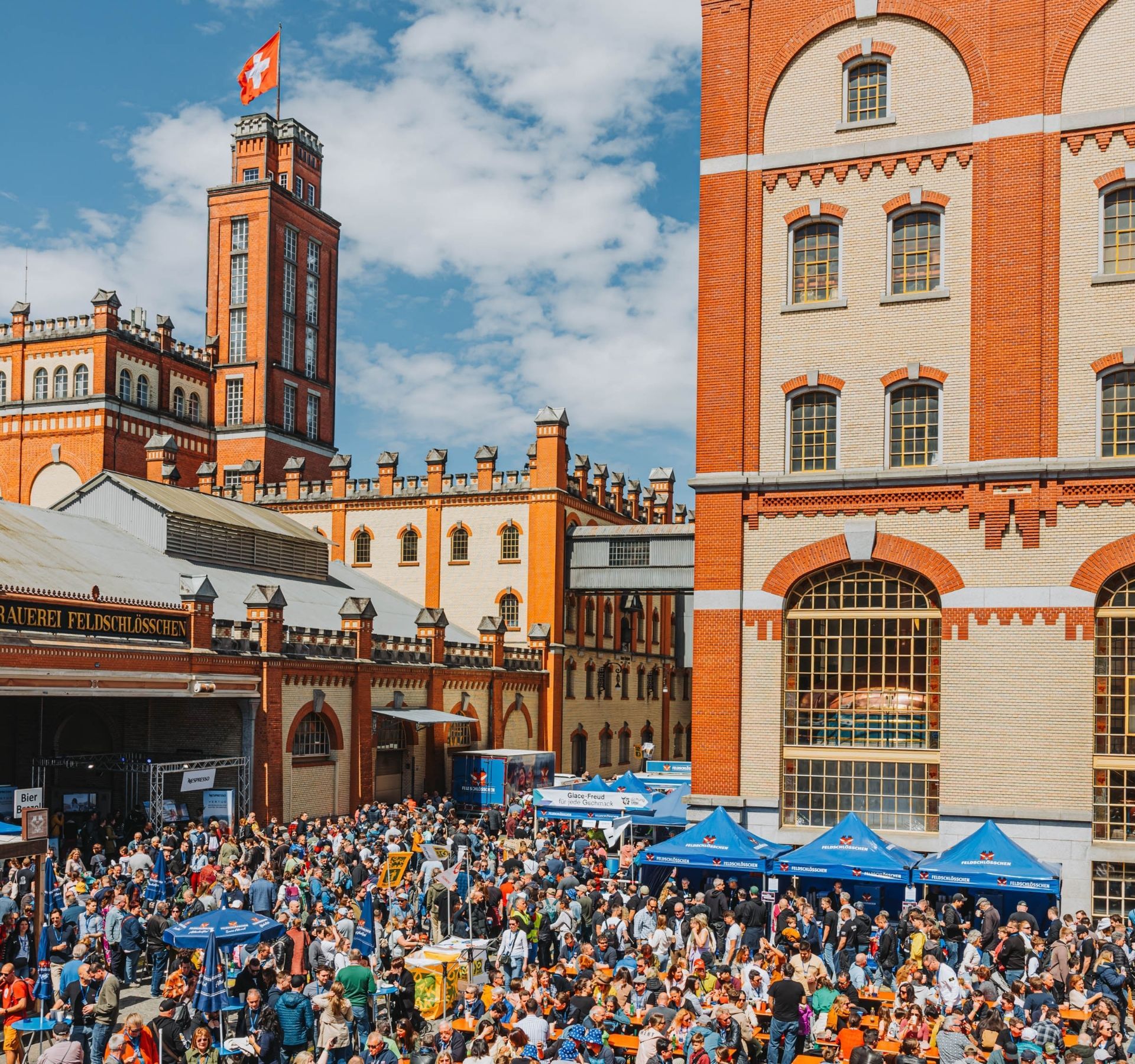 Persone che si godono il Feldschlösschen Brauereifest all’aperto sotto il sole.
