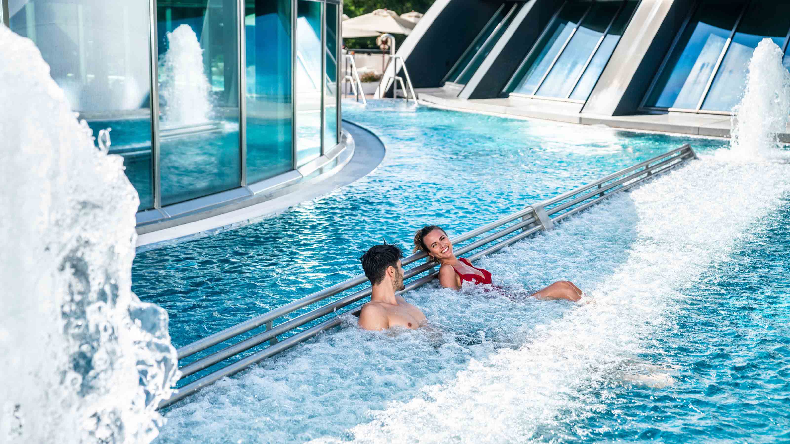 Ein Paar liegt in einem Spurdelbad auf einer Liege und geniesst das wohlig warme Wasser.