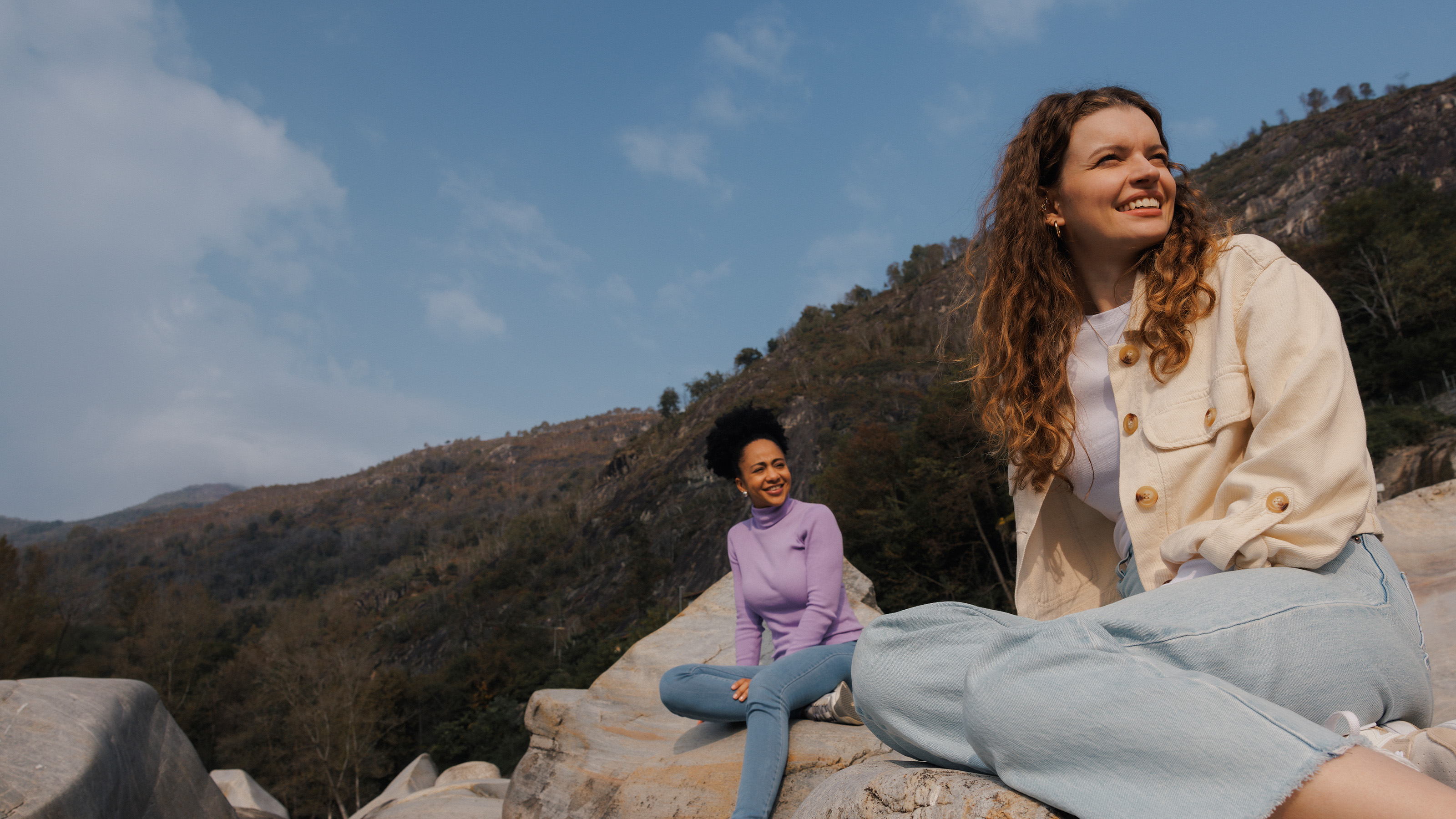  Deux jeunes femmes sont assises sur un gros rocher au soleil.