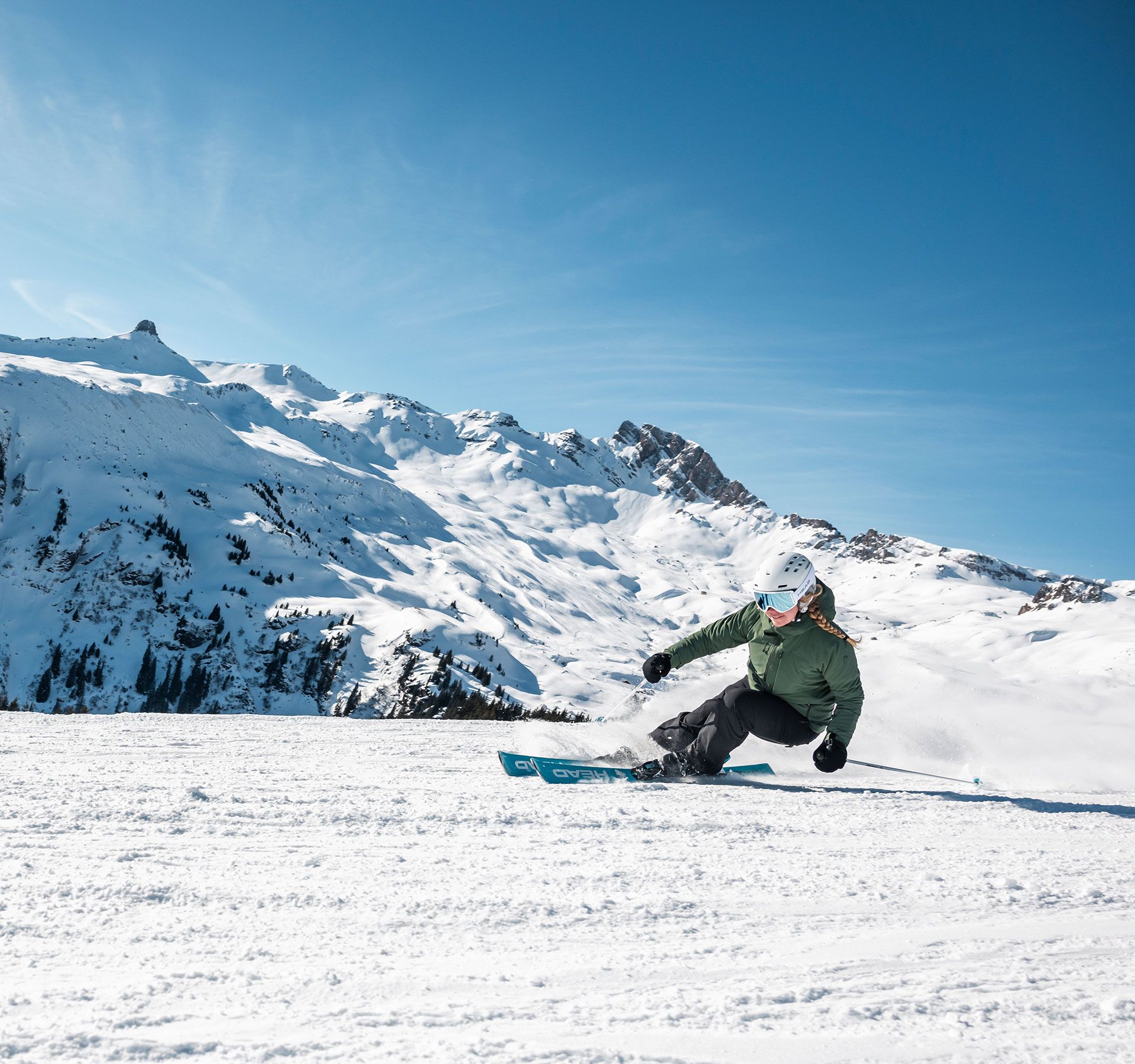 A skier is skiing down the slope, with a beautiful mountain landscape in the background.