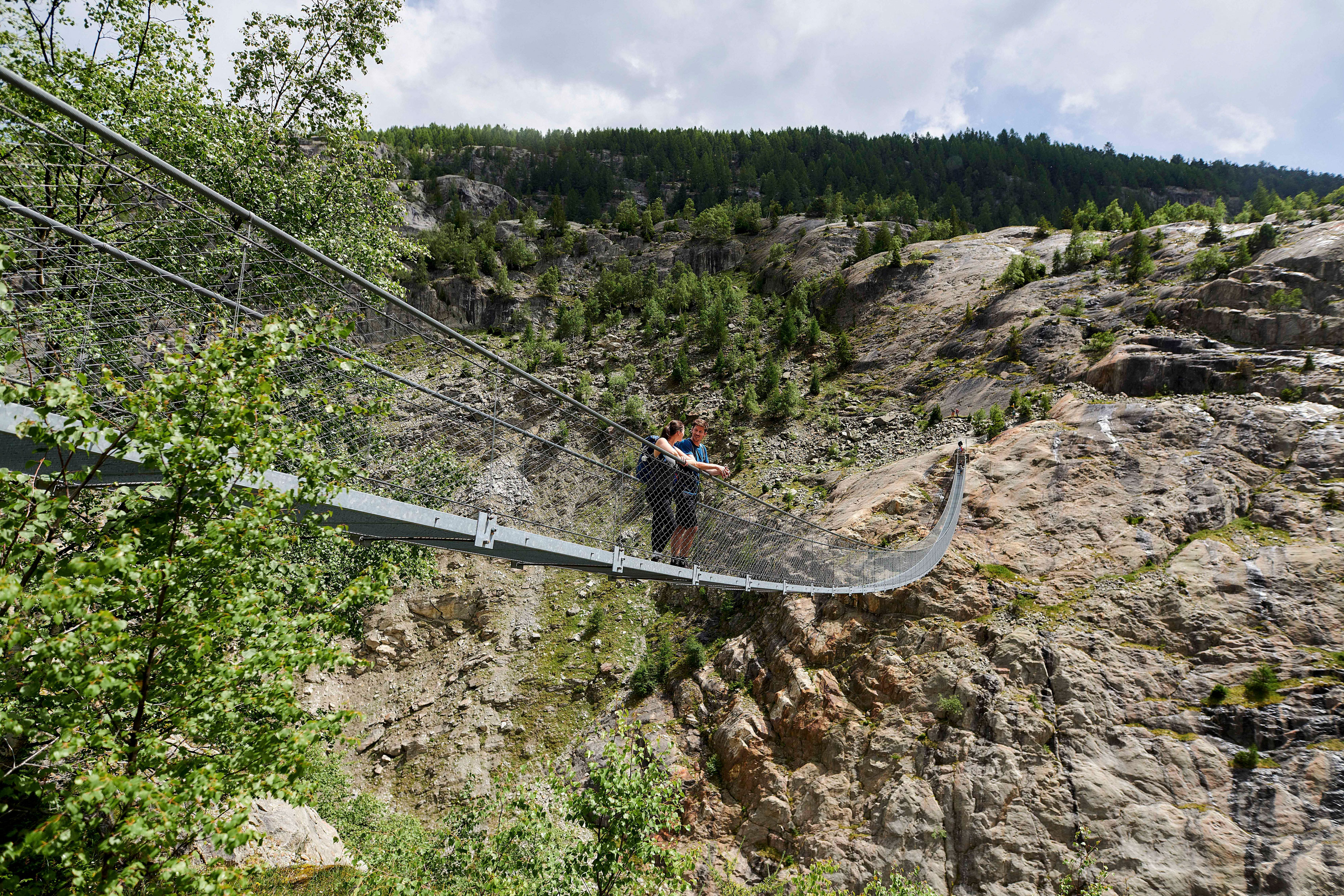 Due persone ammirano la vista spettacolare dalla Ponte sospeso dell'Aletsch.