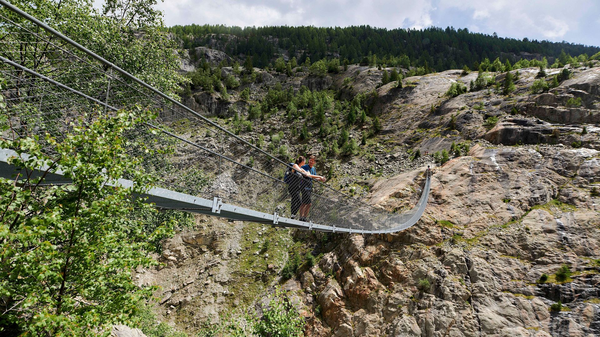 Deux personnes admirent la vue spectaculaire depuis le Pont suspendu de l'Aletsch.