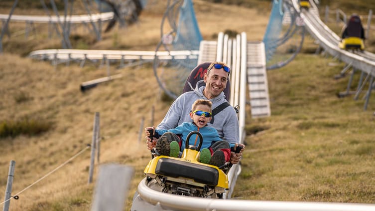 A man and a child ride down the toboggan run together.