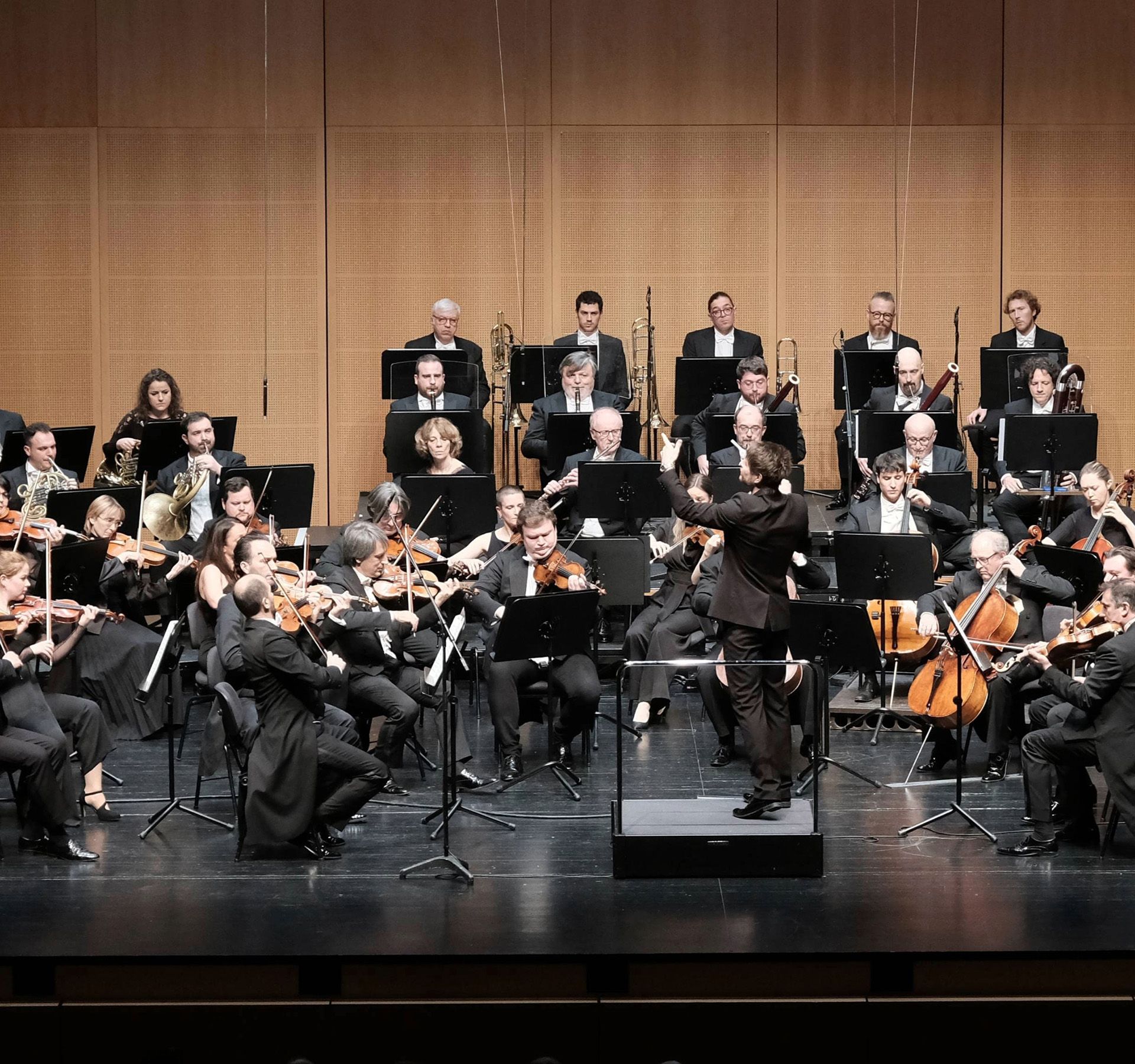 L’Orchestra della Svizzera italiana in concerto, musicisti sul palco con i loro strumenti, diretti dal direttore d’orchestra.