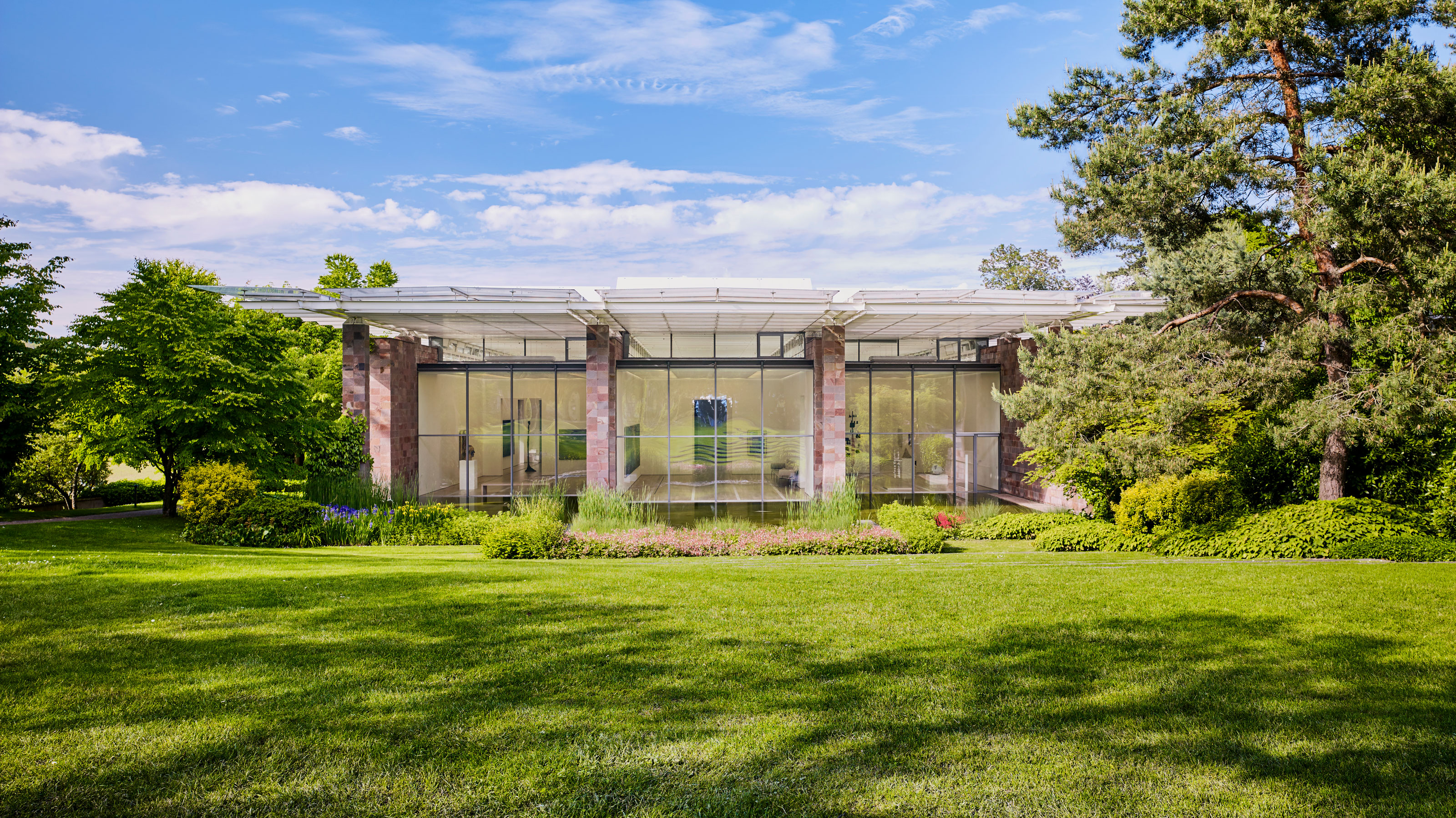 Architettura moderna, circondata da un giardino ben curato e da grandi alberi sotto un cielo azzurro