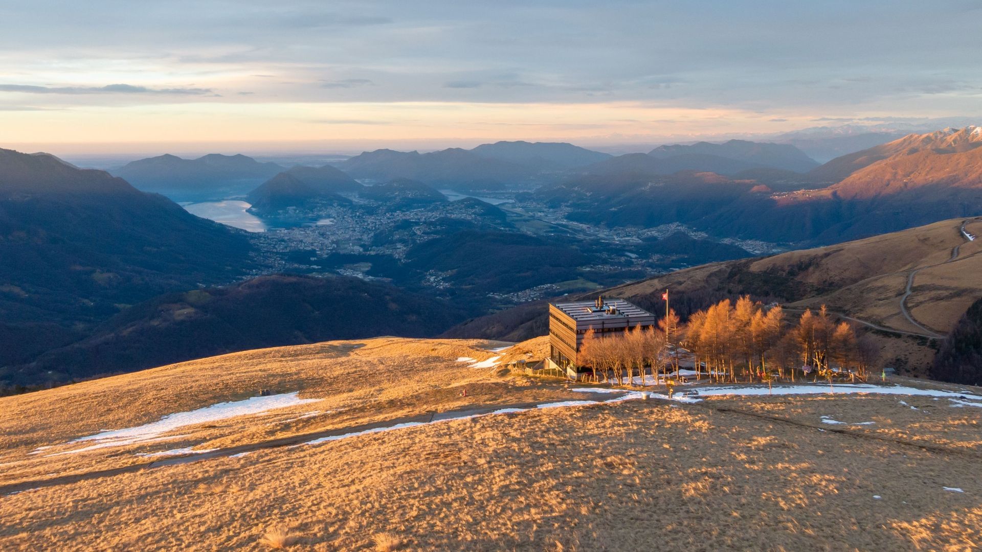 Abendstimmung auf dem Monte Bar mit Blick über die Täler und Seen der Region Lugano. Die warme Sonnenfarbe verleiht der Berglandschaft eine besondere Ruhe.