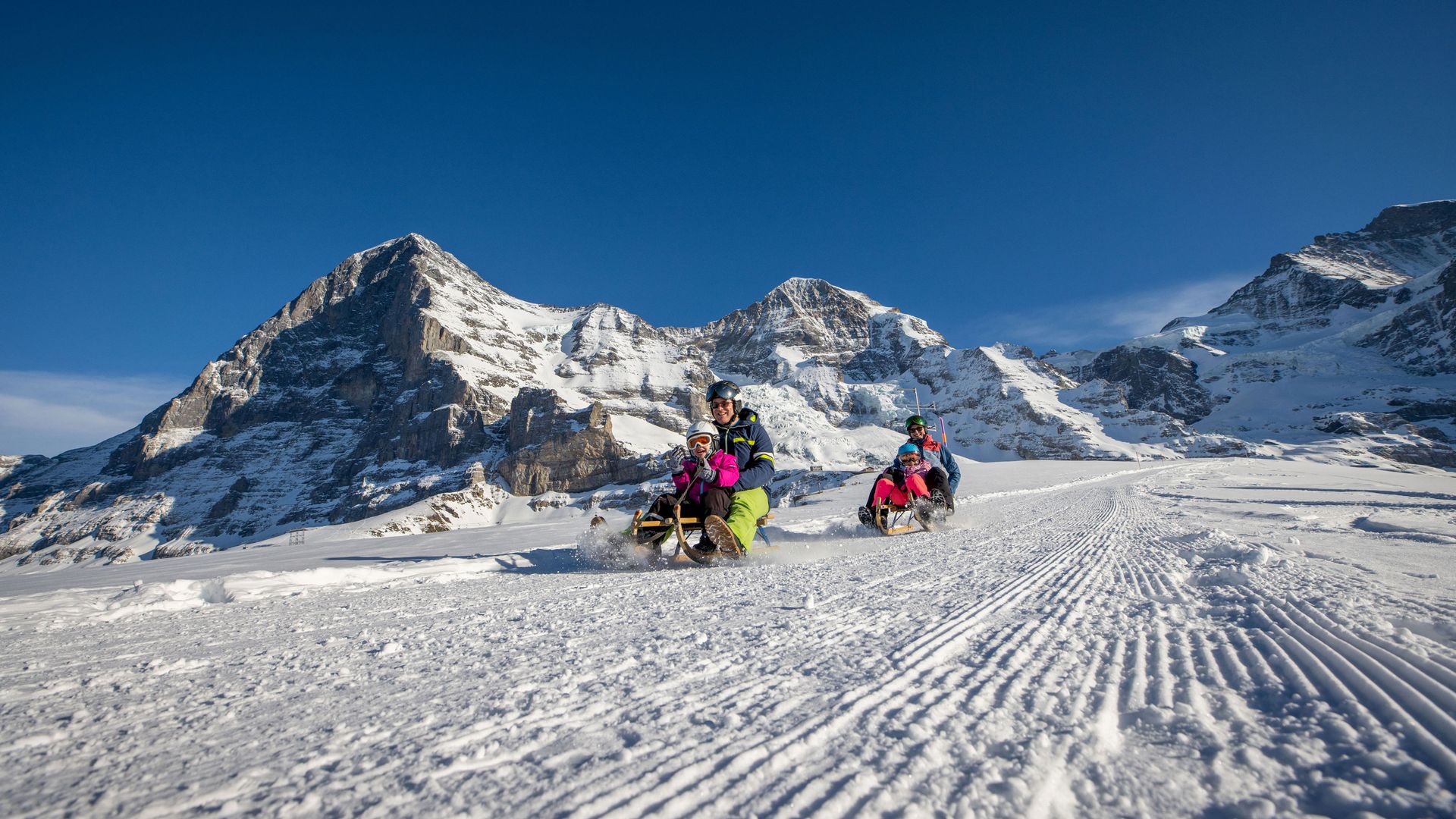 Famille de 4 personnes en luge avec les montagnes en arrières plan