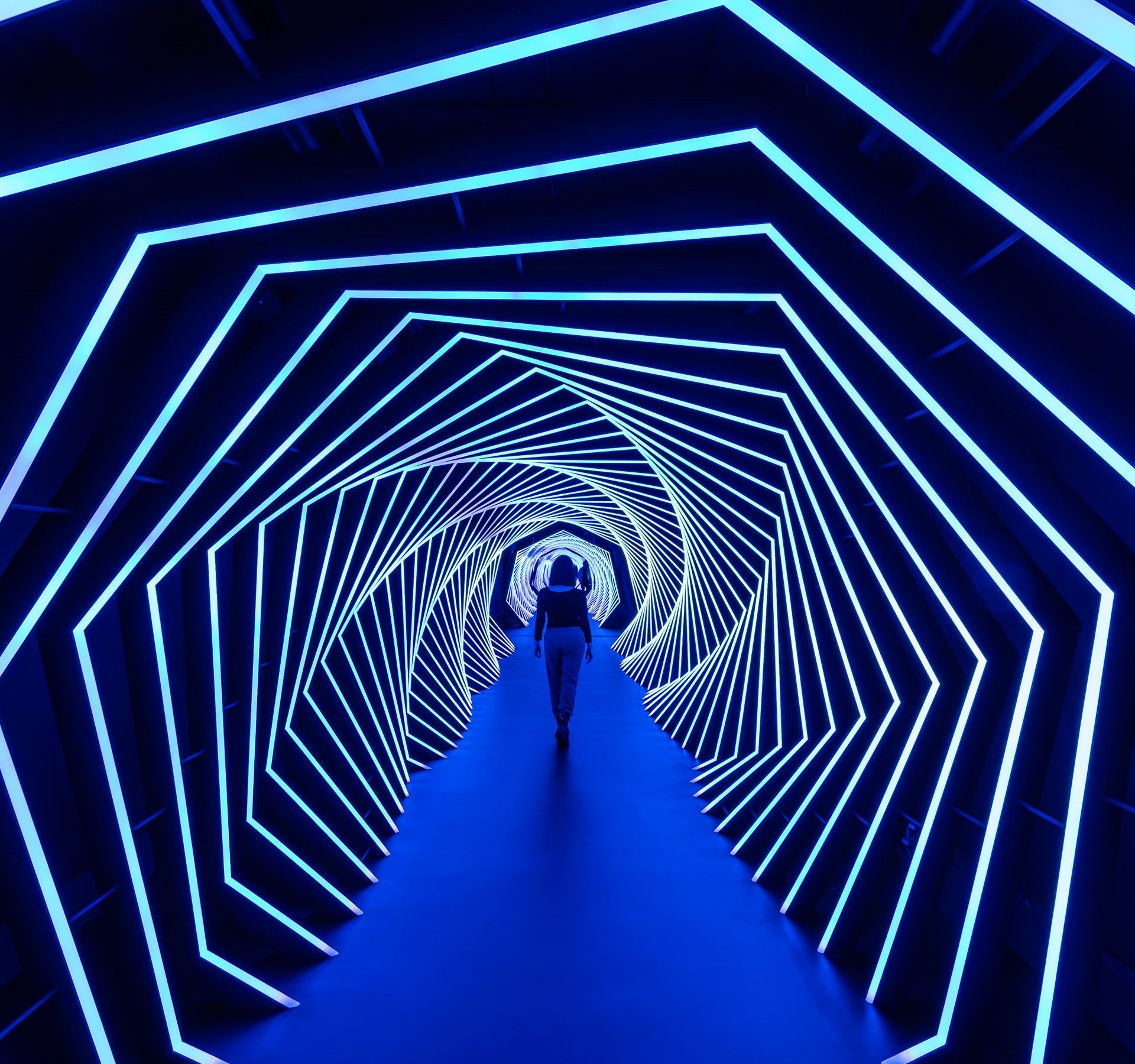 A woman walks through a light tunnel.