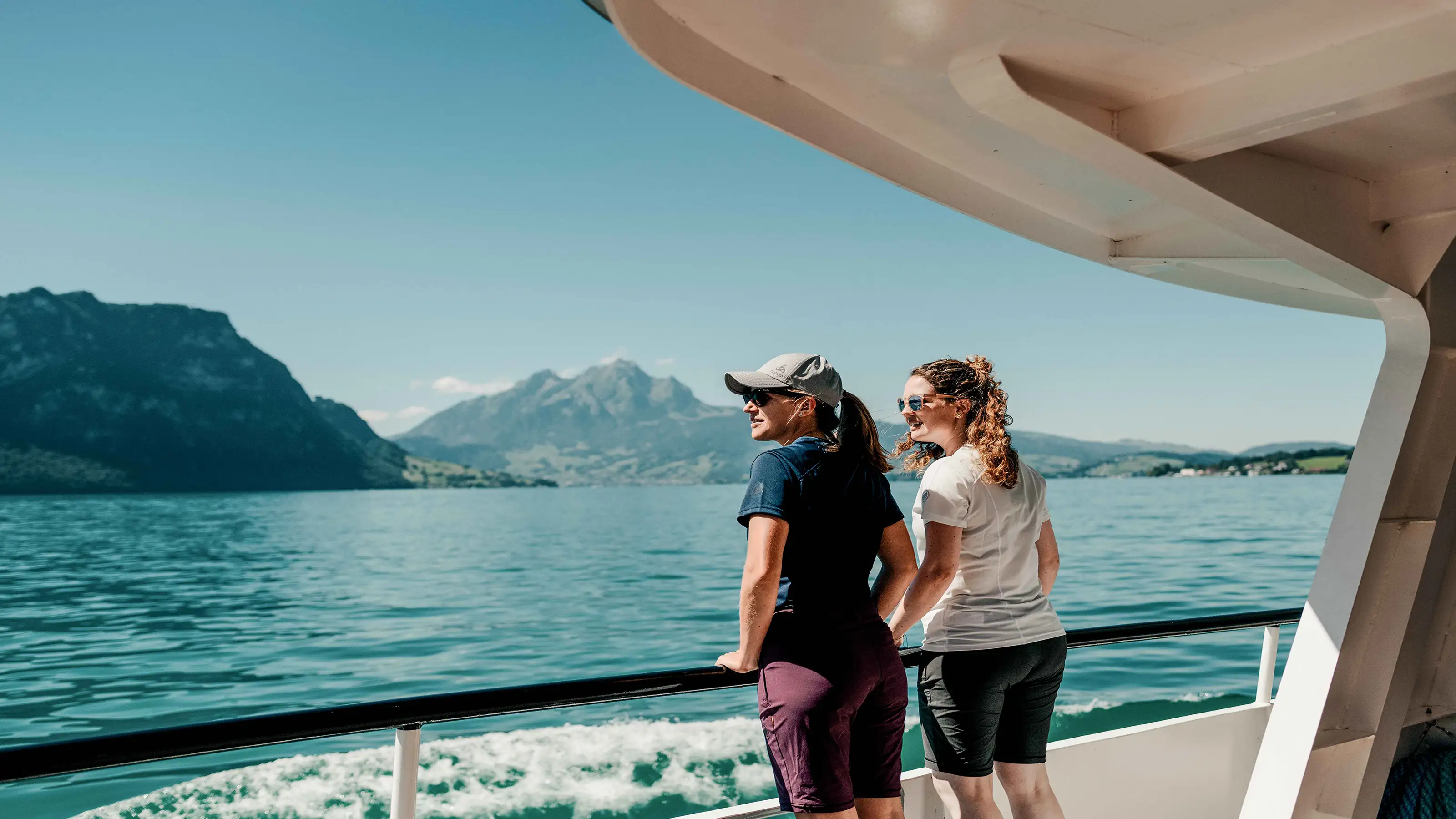 Zwei Frauen stehen auf dem Deck eines Bootes und blicken auf das Wasser.