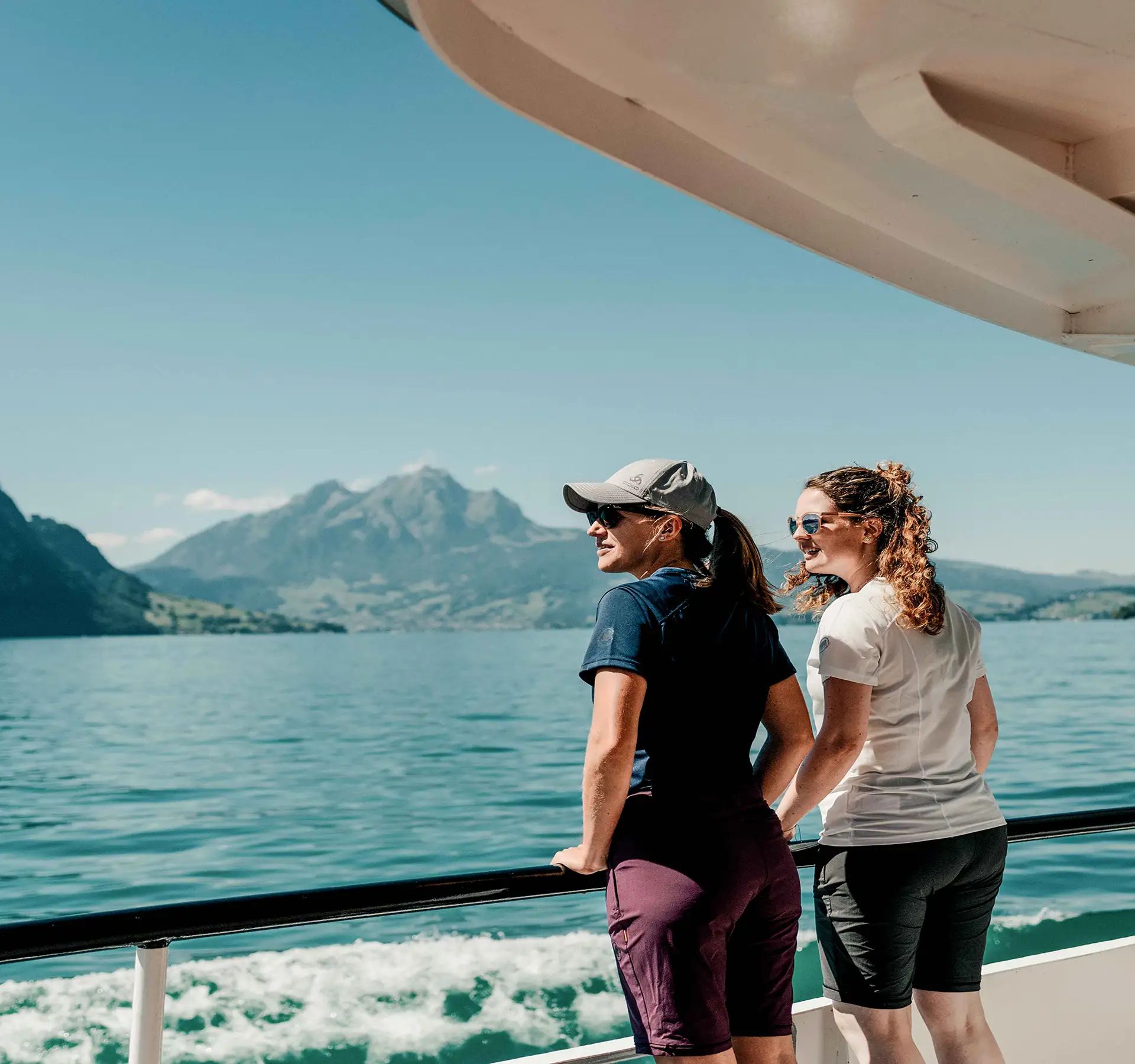 Zwei Frauen stehen auf dem Deck eines Bootes und blicken auf das Wasser.