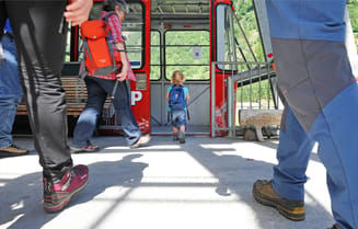A child walks into the cable car cabin with his family. 