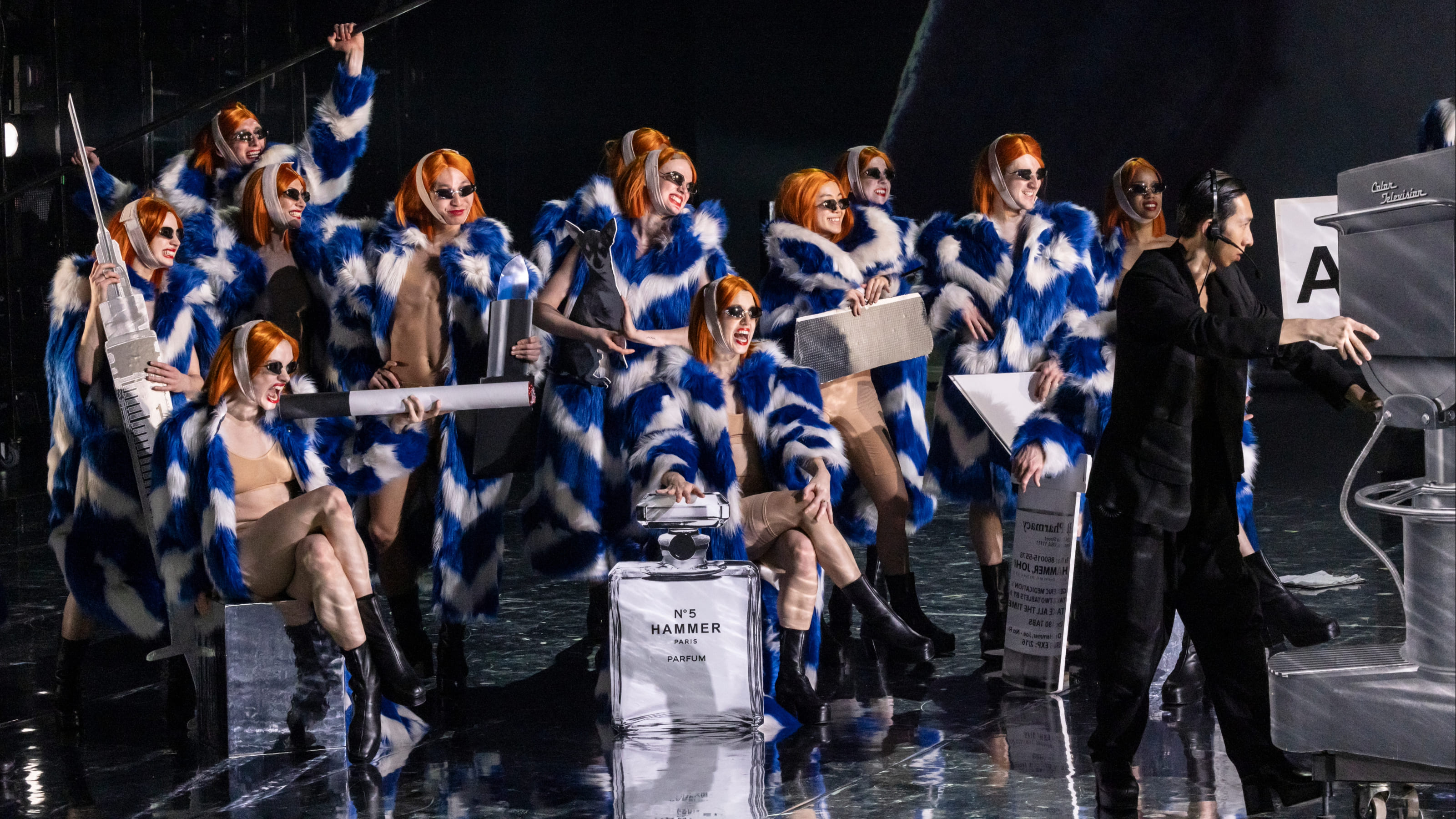 Un gruppo di danza moderno del GöteborgsOperans Danskompani che si esibisce su un palco illuminato intensamente a Lugano; movimenti dinamici, linee pulite, atmosfera contemporanea.