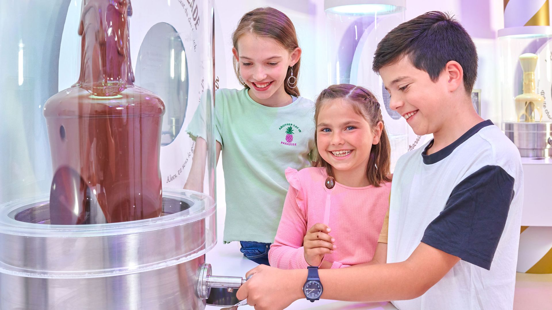 Three happy children testing chocolate from the chocolate fountain.