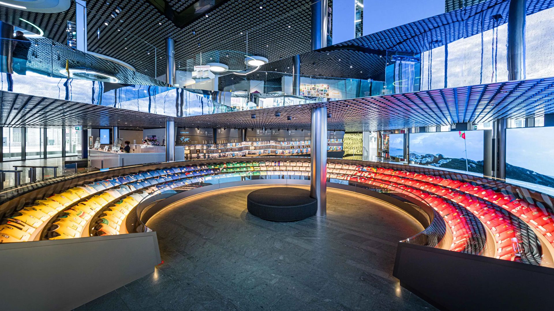 Inside a modern building stands a large glass statue reminiscent of a stadium.
