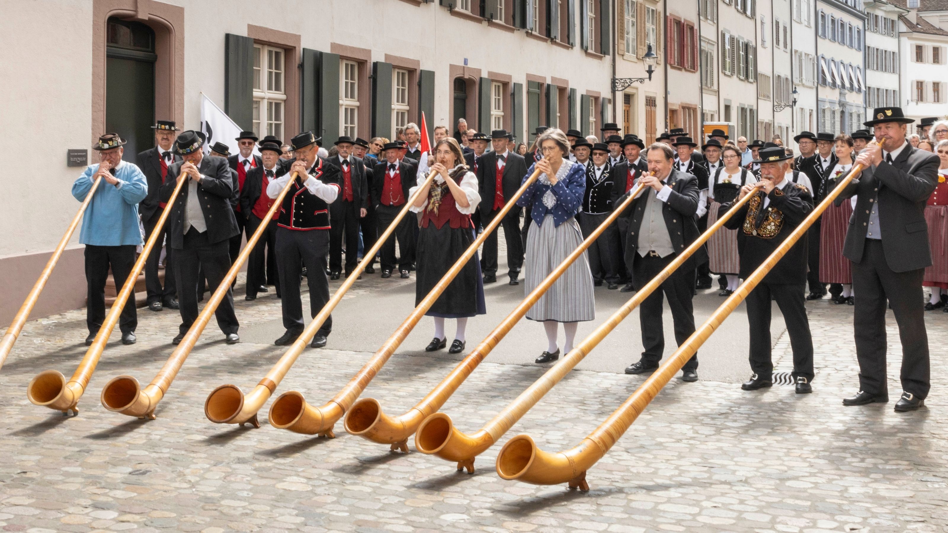 Fotografia storica in bianco e nero di un gruppo di jodler in costume tradizionale durante un’esibizione su una piazza festiva.