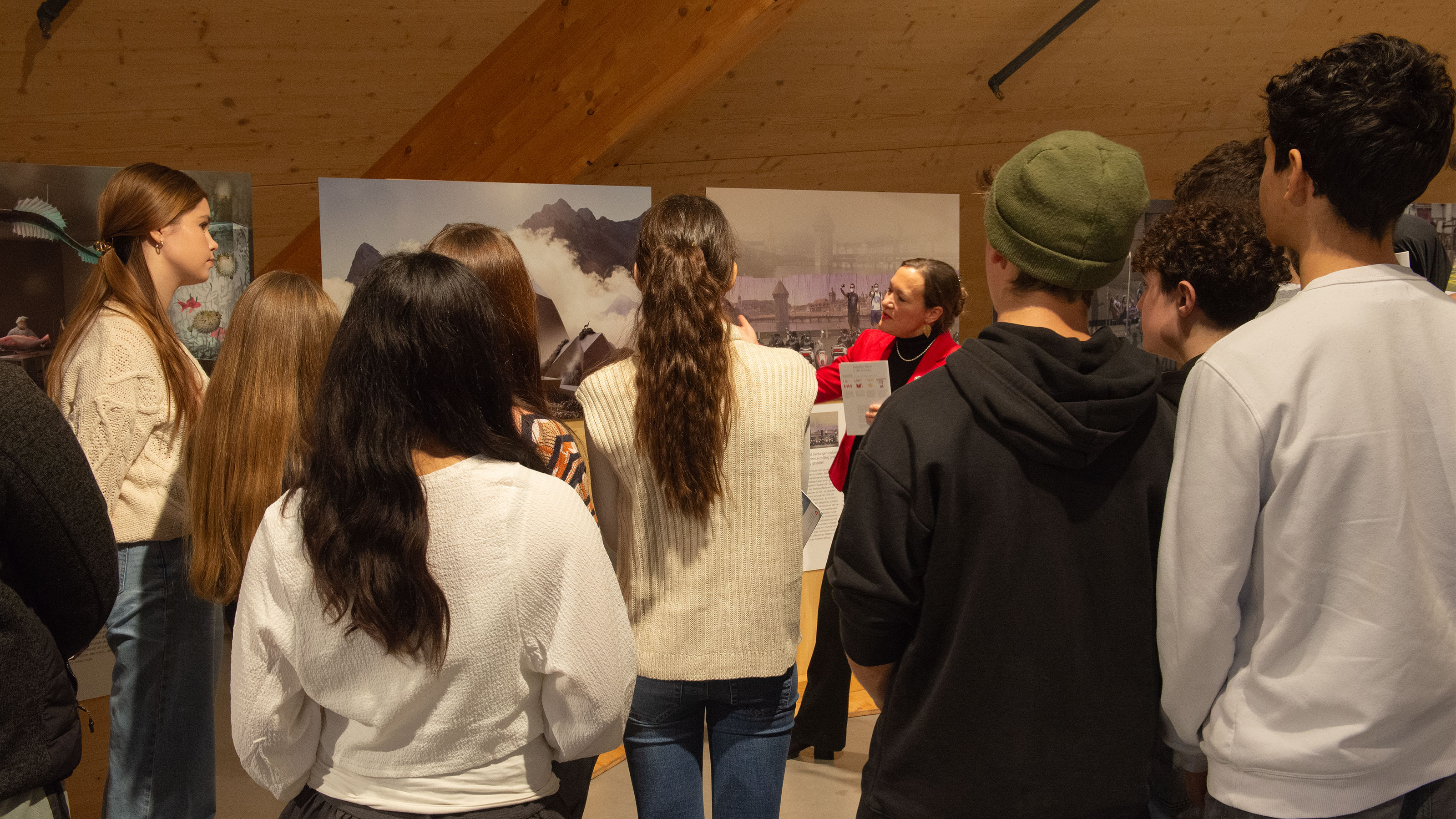A group of pupils gathers around a poster and listens to a guided tour.