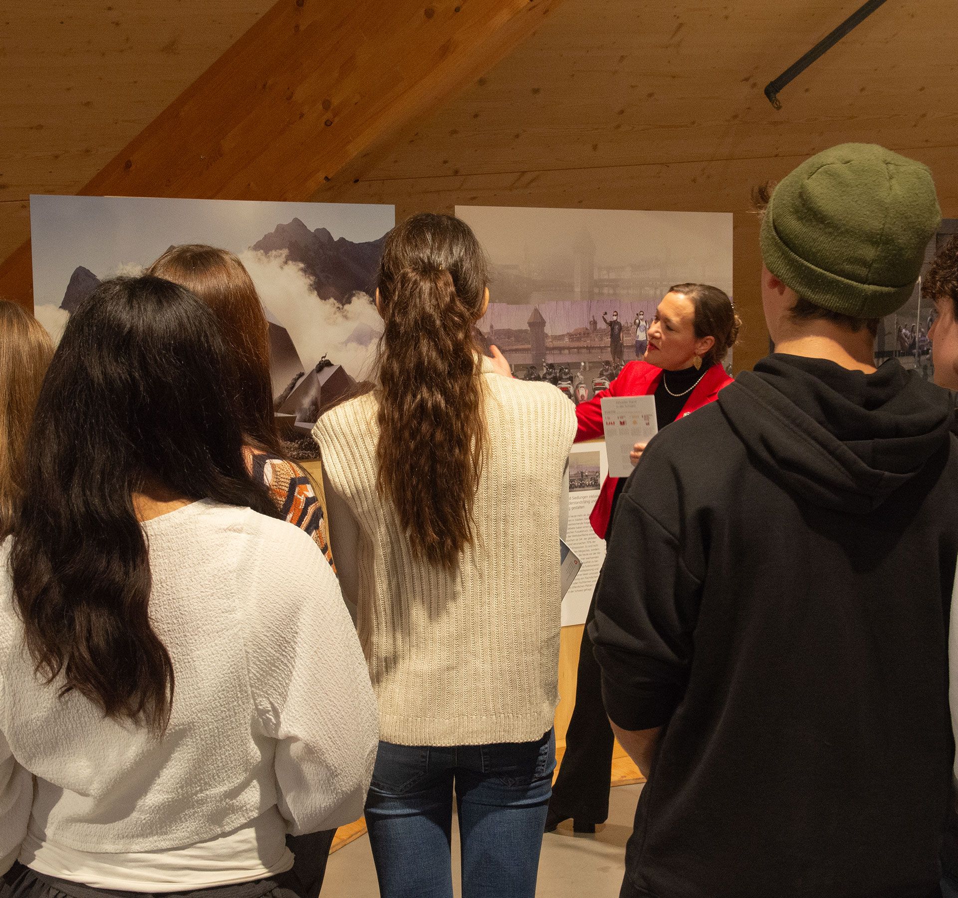 Un groupe d'élèves se rassemble autour d'une affiche et écoute une visite guidée.