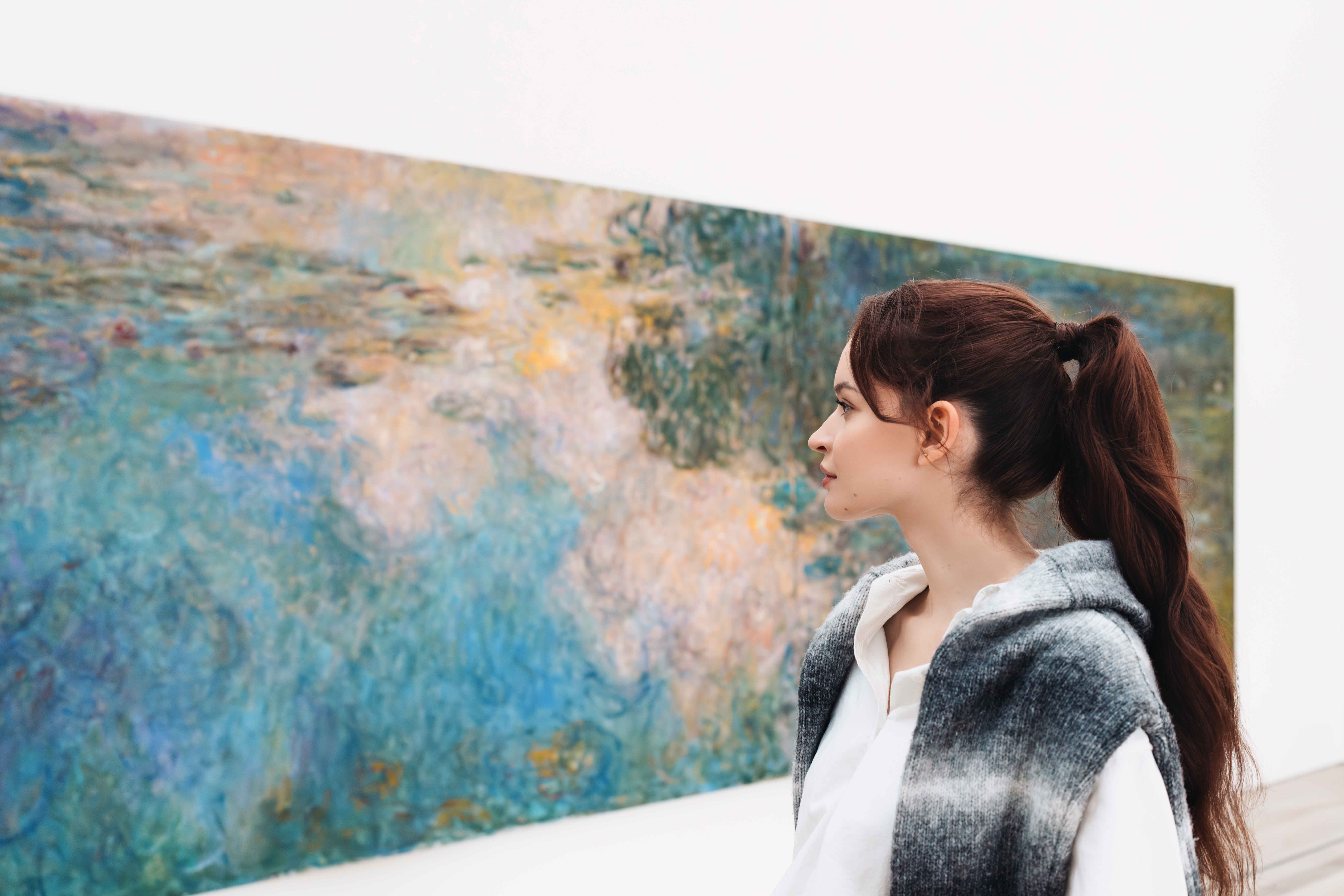 Eine Frau betrachtet ein Gemälde in einer Kunstgalerie.