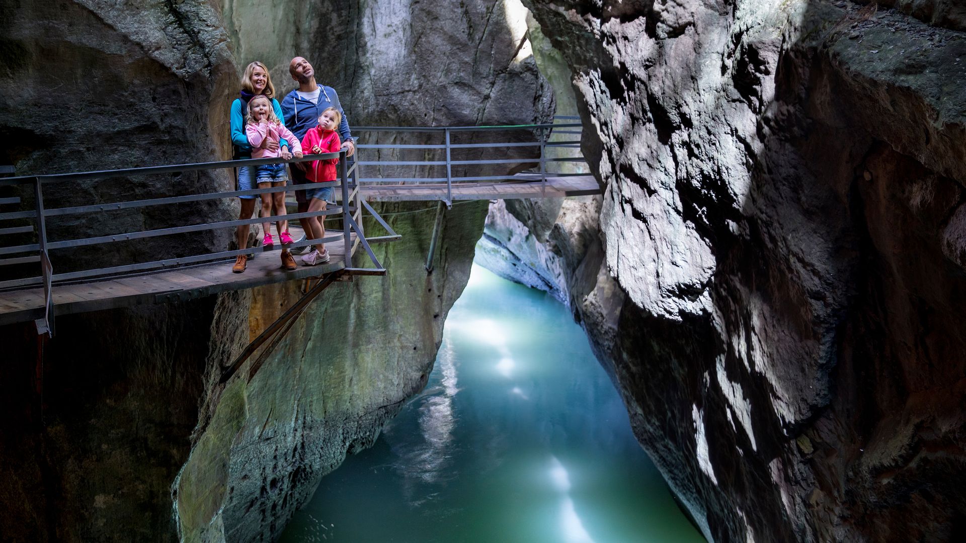 Eine Familie mit zwei Töchtern steht auf einer Brücke in der Aareschlucht.