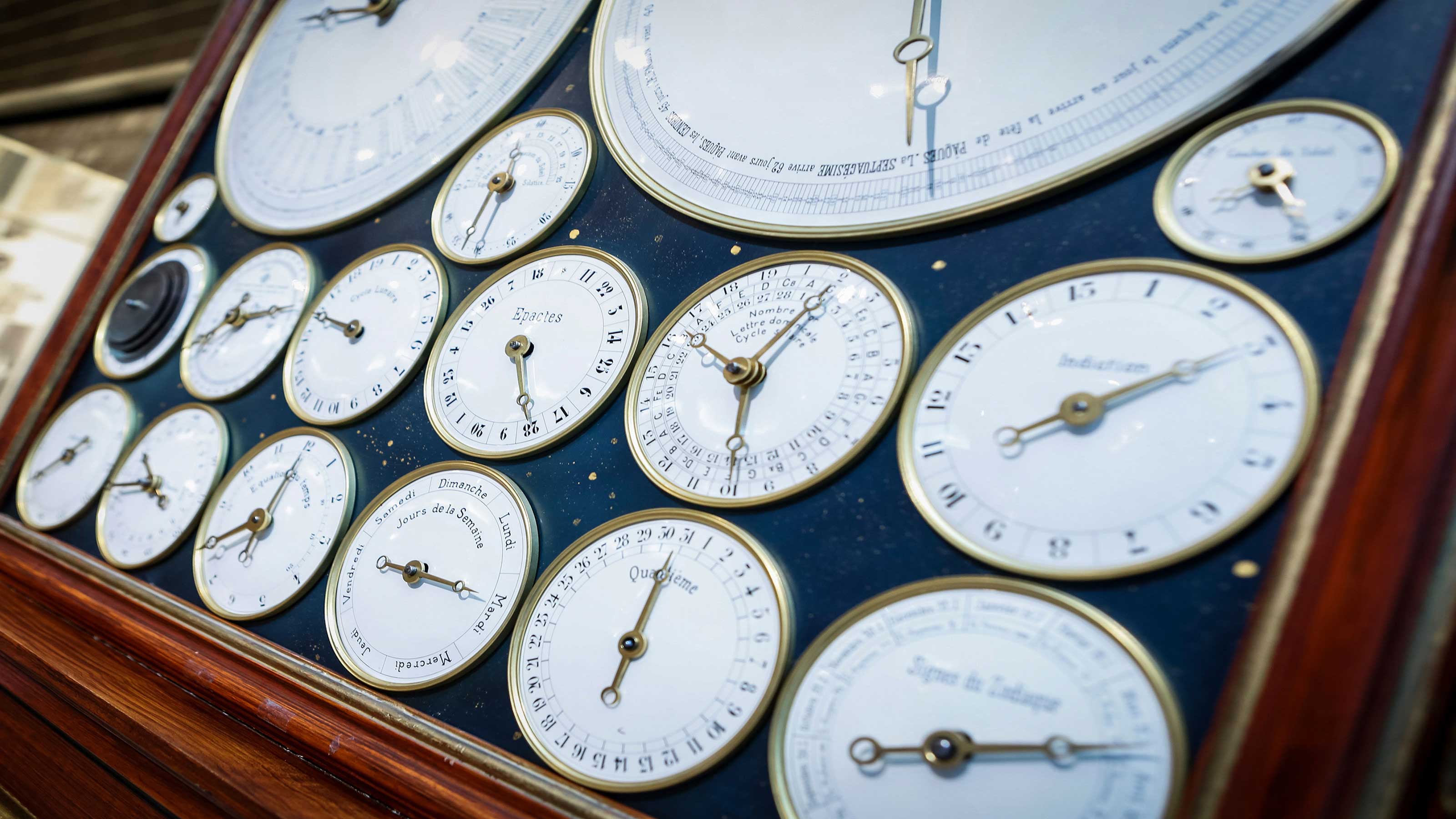 L'immagine mostra vecchi quadranti di orologi in una cornice con sfondo blu.