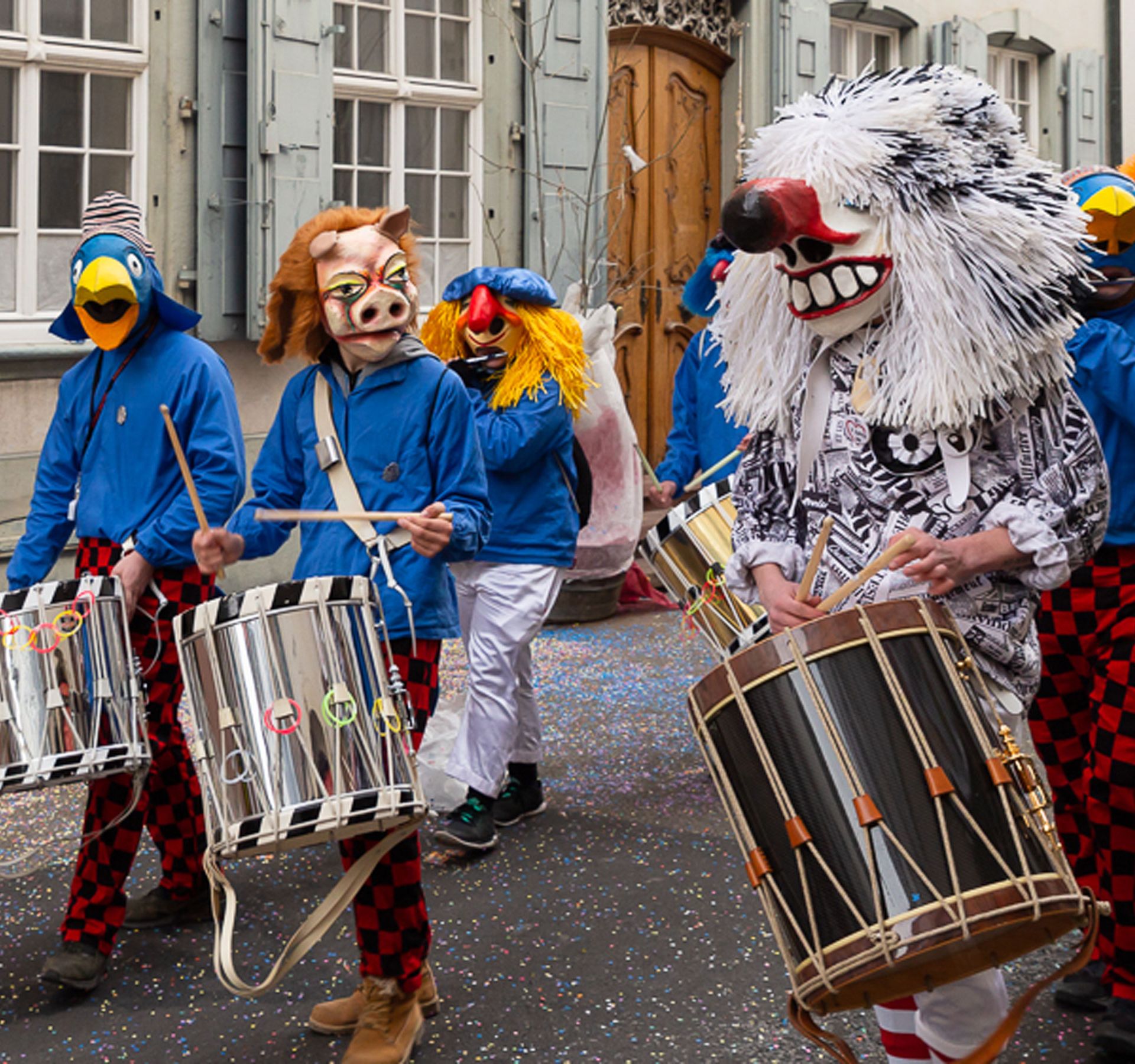 People in colorful masks parading through the streets of Basel during carnival.