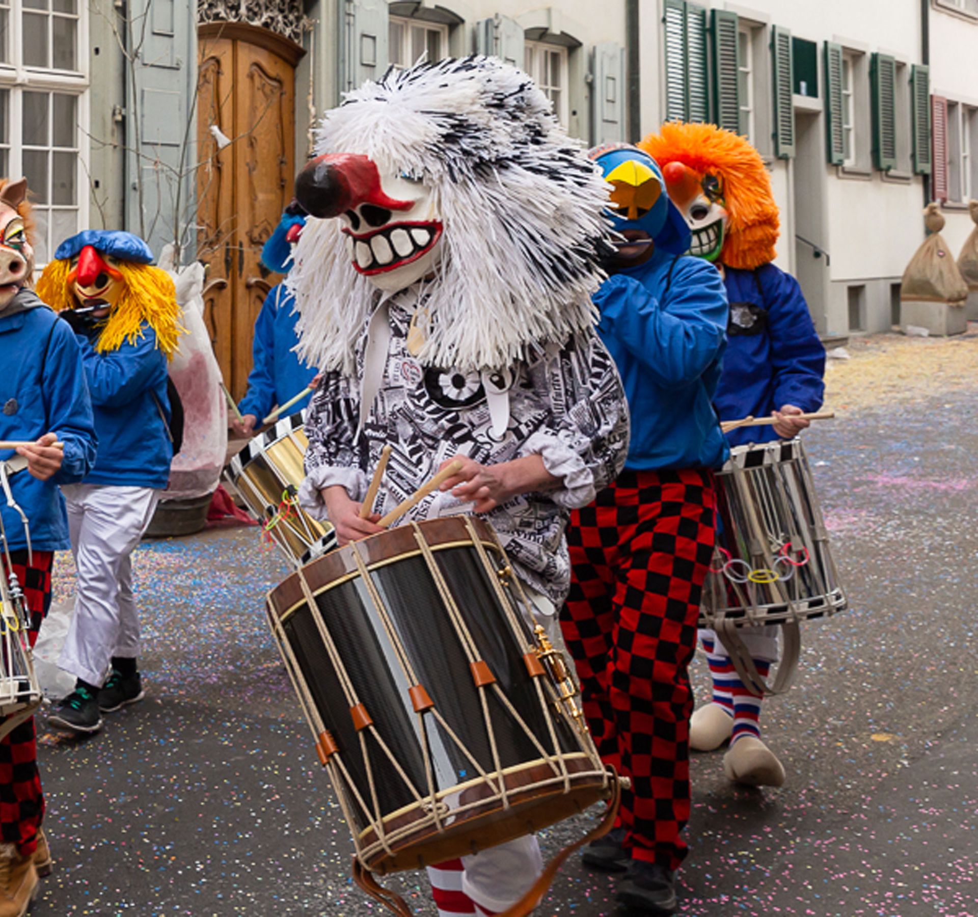 Menschen in bunten Masken ziehen durch die Strassen von Basel während der Fasnacht.