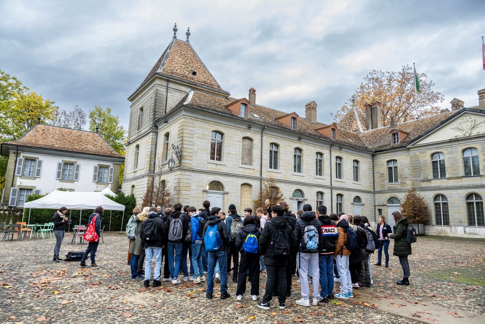 Eine Schulklasse versammelt sich vor dem Château de Prangins. Das Foto wurde von hinter der Gruppe aufgenommen, damit man das Château im Hintergrund sehen kann.