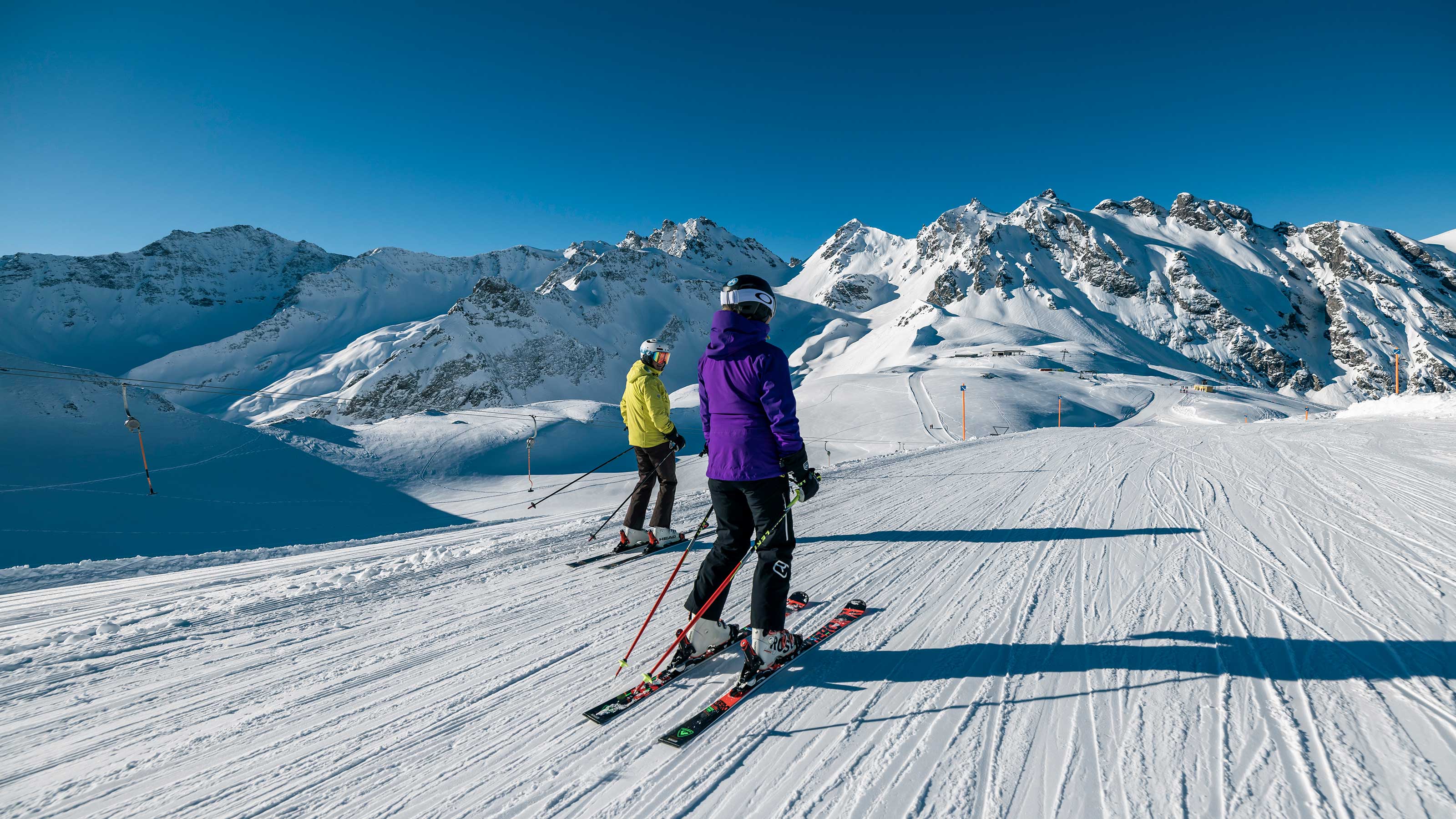 Due sciatori che navigano in un paesaggio montano innevato, mettendo in mostra le loro abilità su uno sfondo di neve bianca incontaminata.