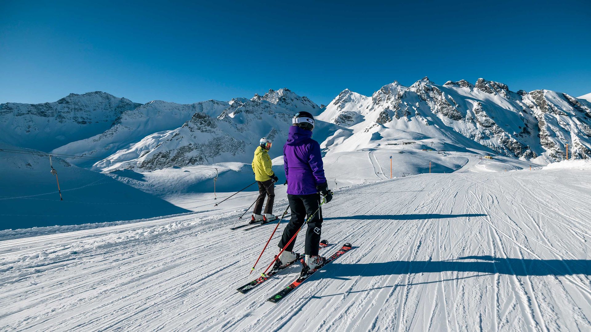 Due sciatori che navigano in un paesaggio montano innevato, mettendo in mostra le loro abilità su uno sfondo di neve bianca incontaminata.